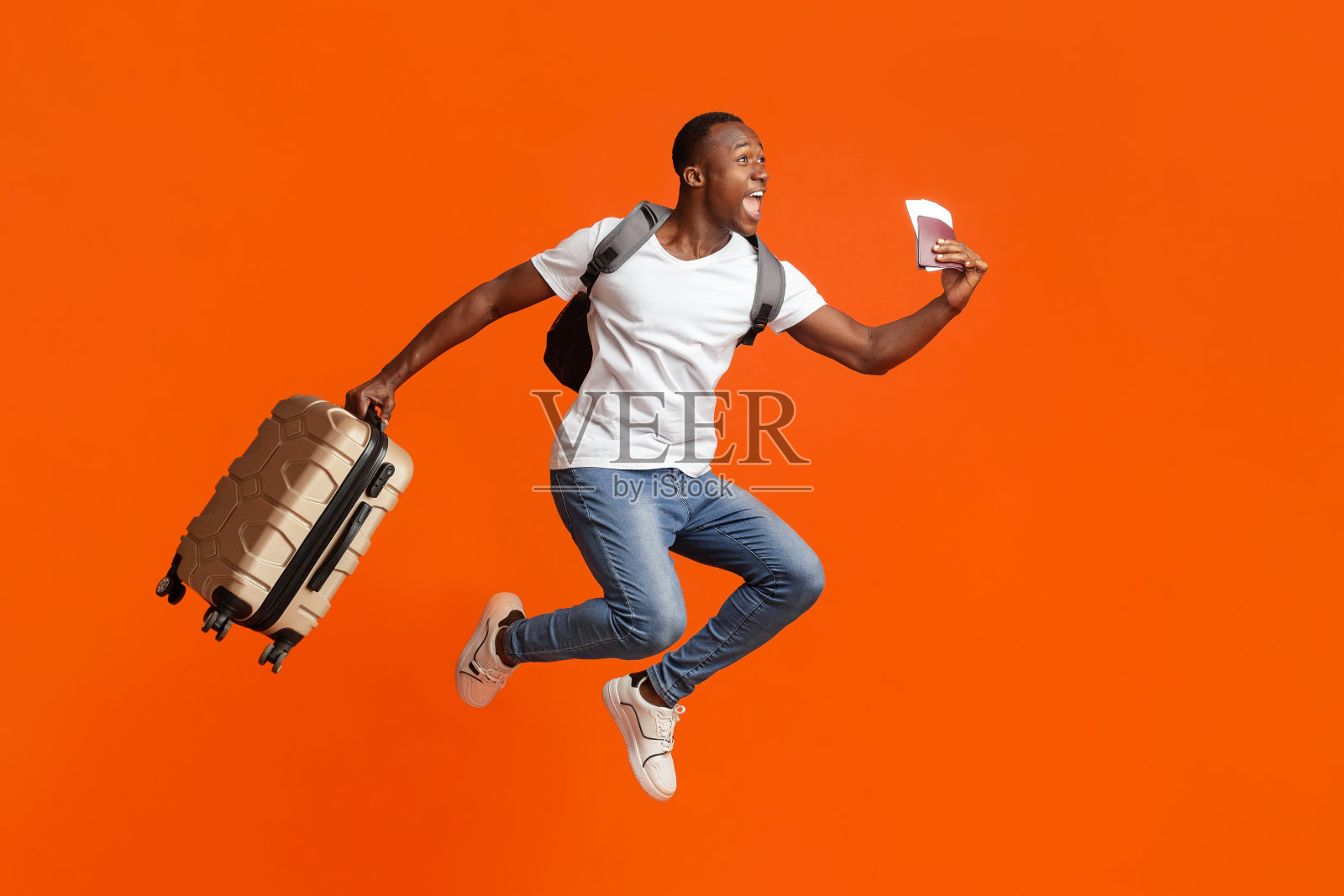 一个带着护照和行李箱的快乐黑人跳了起来照片摄影图片