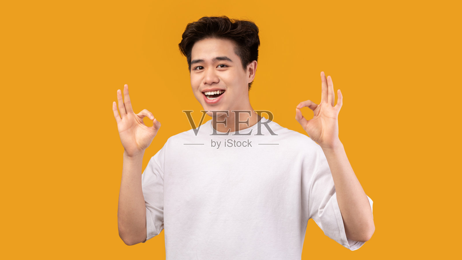 快乐的亚洲男人打了个手势，然后微笑照片摄影图片