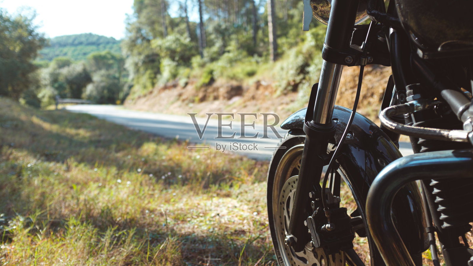 一辆黑色的摩托车停在路边，一条绿色的山道蜿蜒曲折照片摄影图片