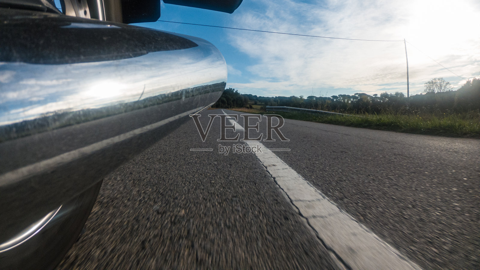 铬排气管上的老式摩托车骑在柏油马路上向后看照片摄影图片