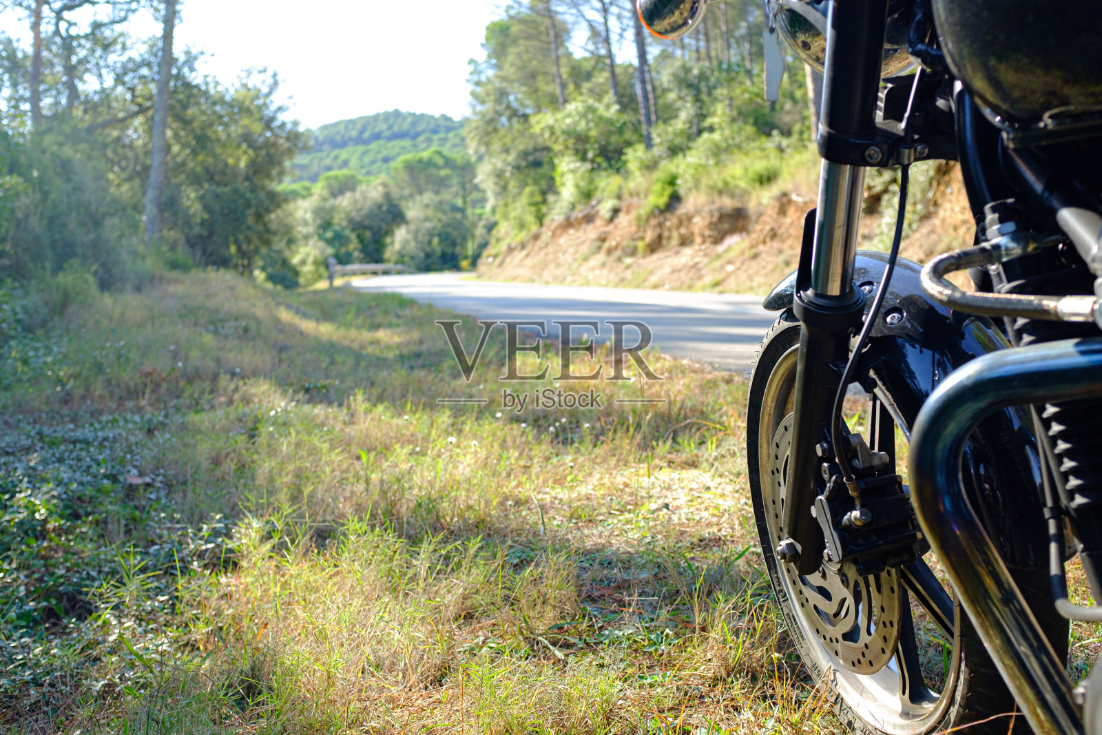 一辆黑色的摩托车停在路边，一条绿色的山道蜿蜒曲折照片摄影图片