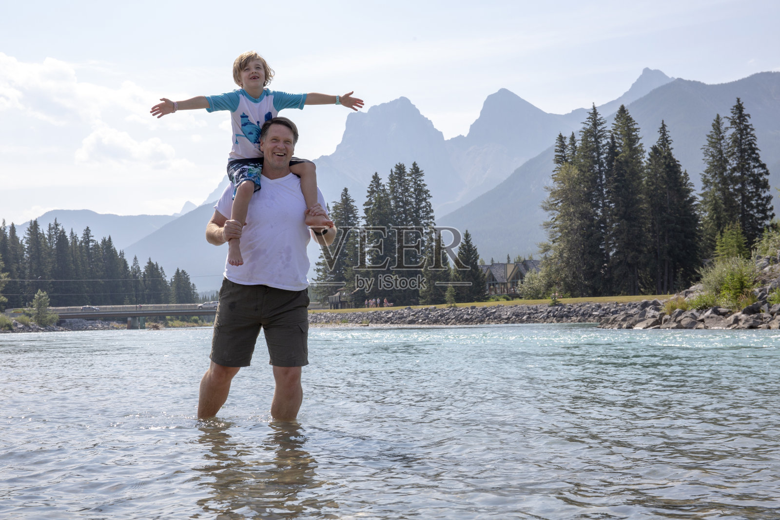父亲和儿子在早晨穿过流动的河流照片摄影图片