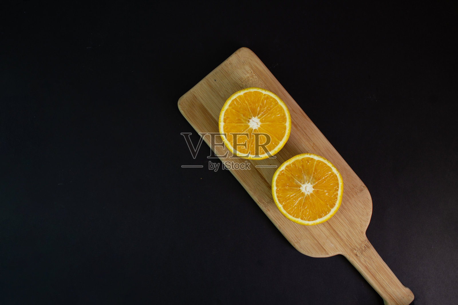 餐桌上优雅的黑色背景上，对半橘色。健康的食物照片摄影图片