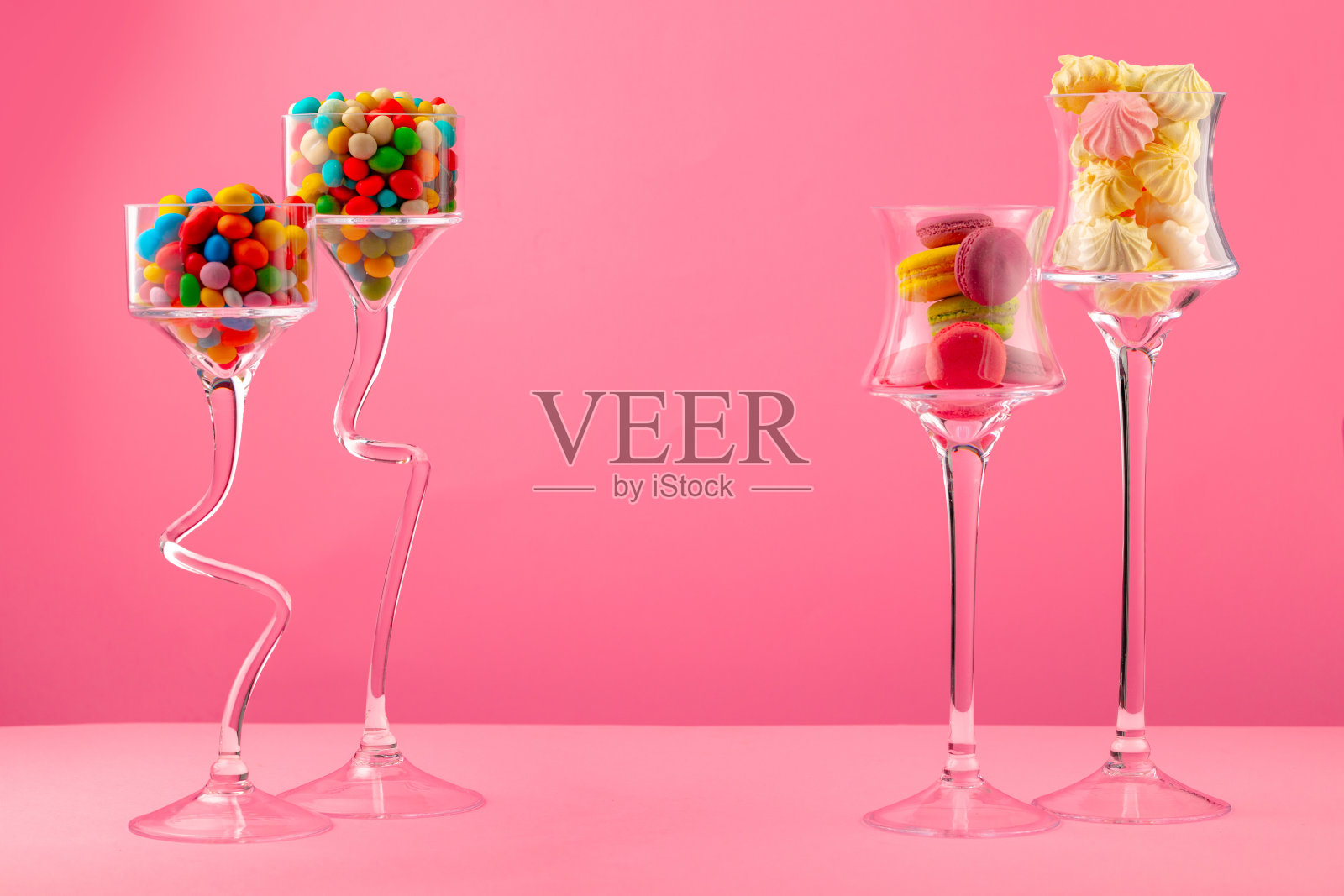 粉红色背景下装有糖果的玻璃容器照片摄影图片