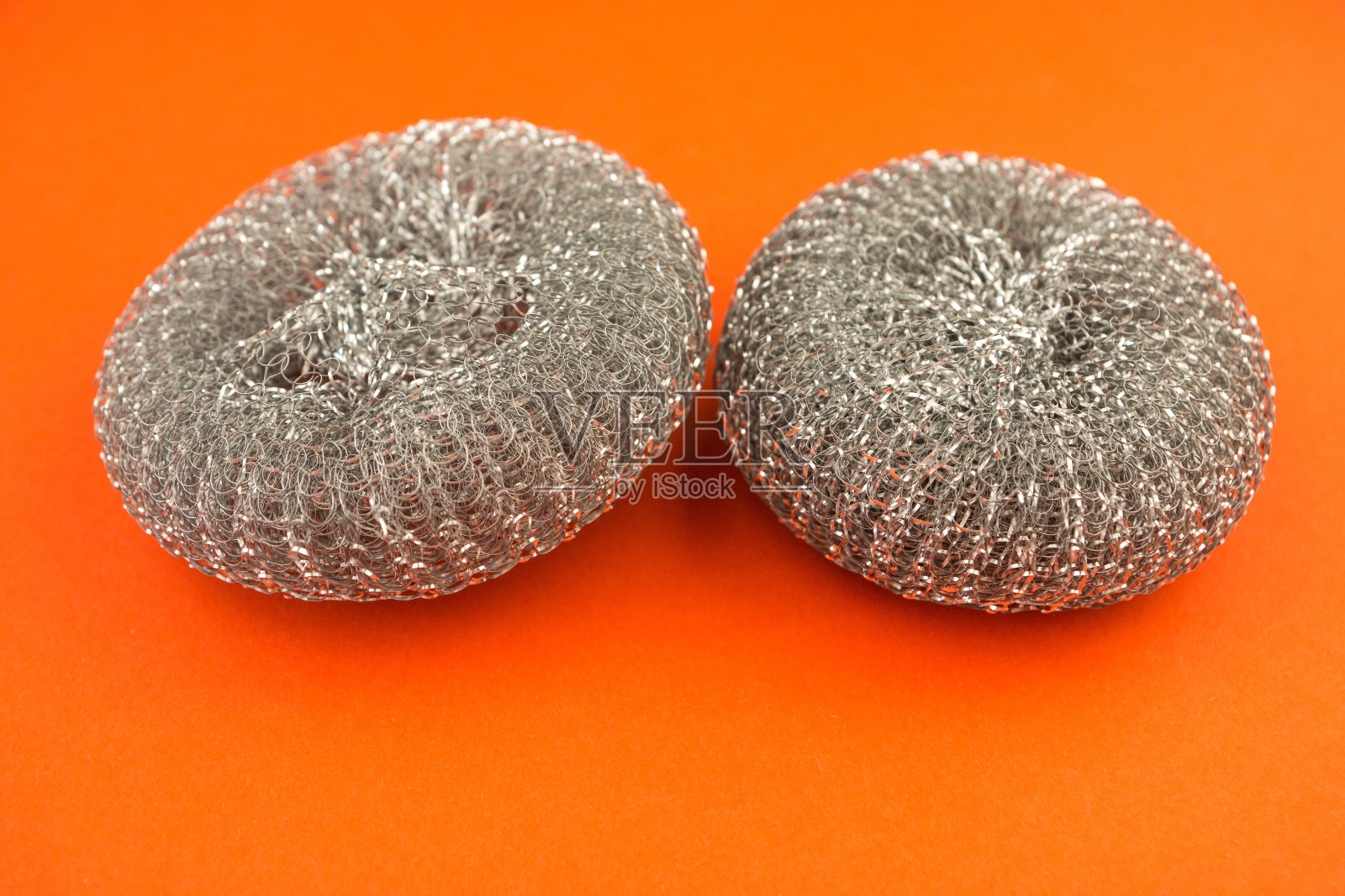 特写的新金属海绵洗涤锅在明亮的橙色背景。洗盘子用的厨房用具。有选择性的重点。照片摄影图片