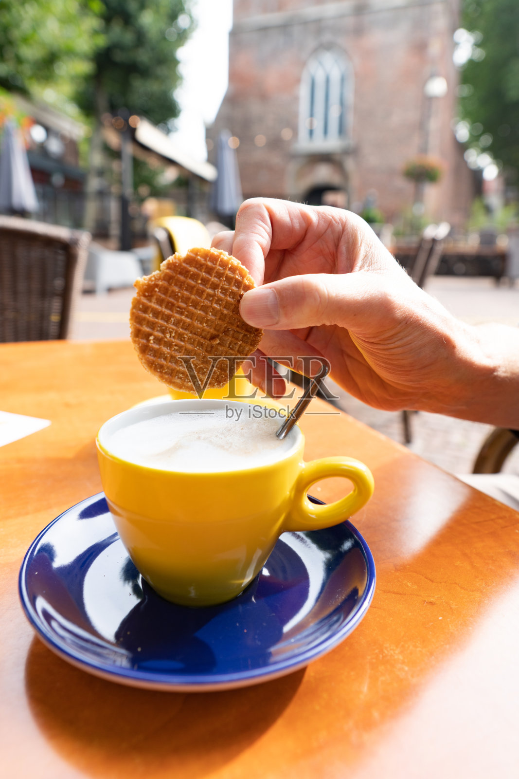 一名男子在他的卡布奇诺中蘸了一块典型的荷兰焦糖饼干(stroopwafel)照片摄影图片