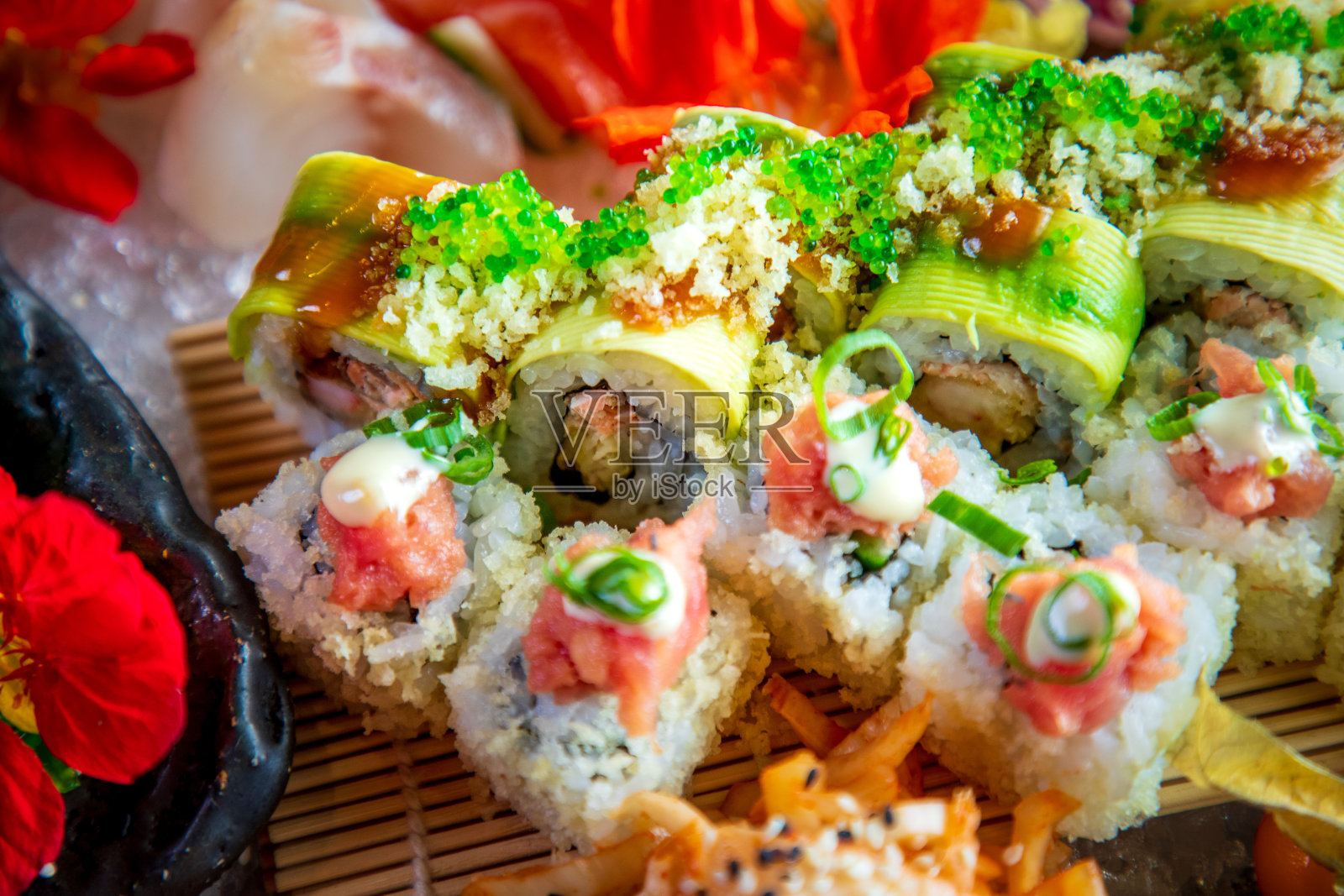 特写寿司卷与鱼子酱顶部，在碗上的冰照片摄影图片