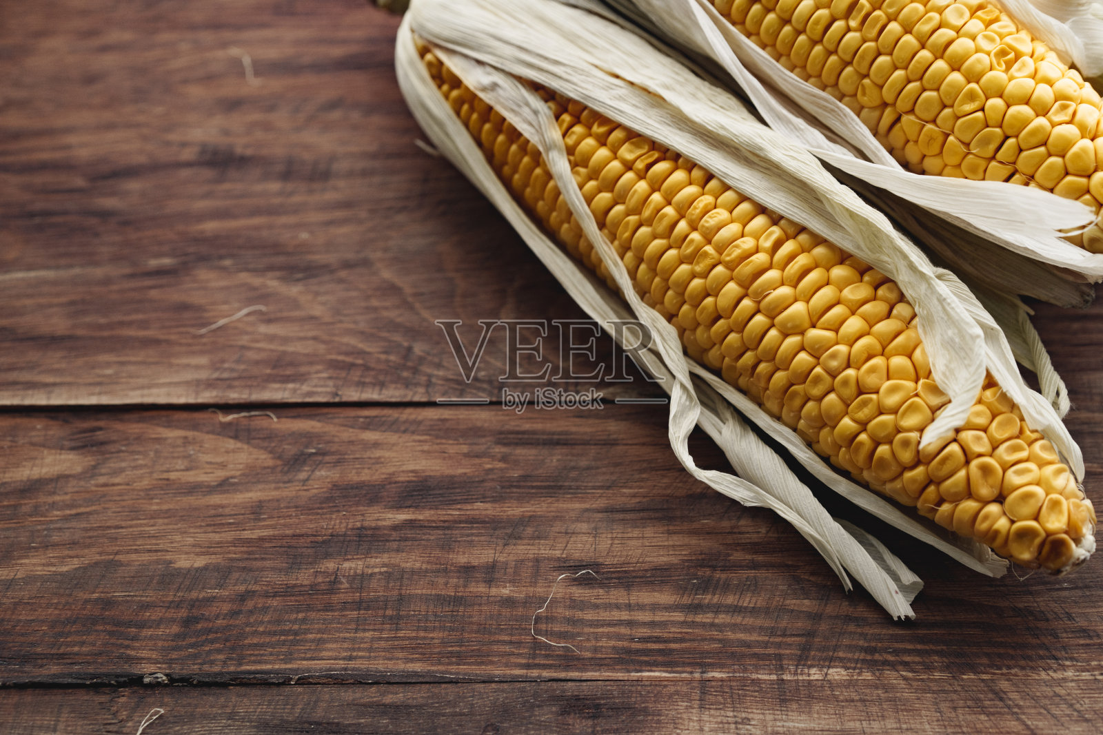 玉米棒放在深棕色的木桌上照片摄影图片