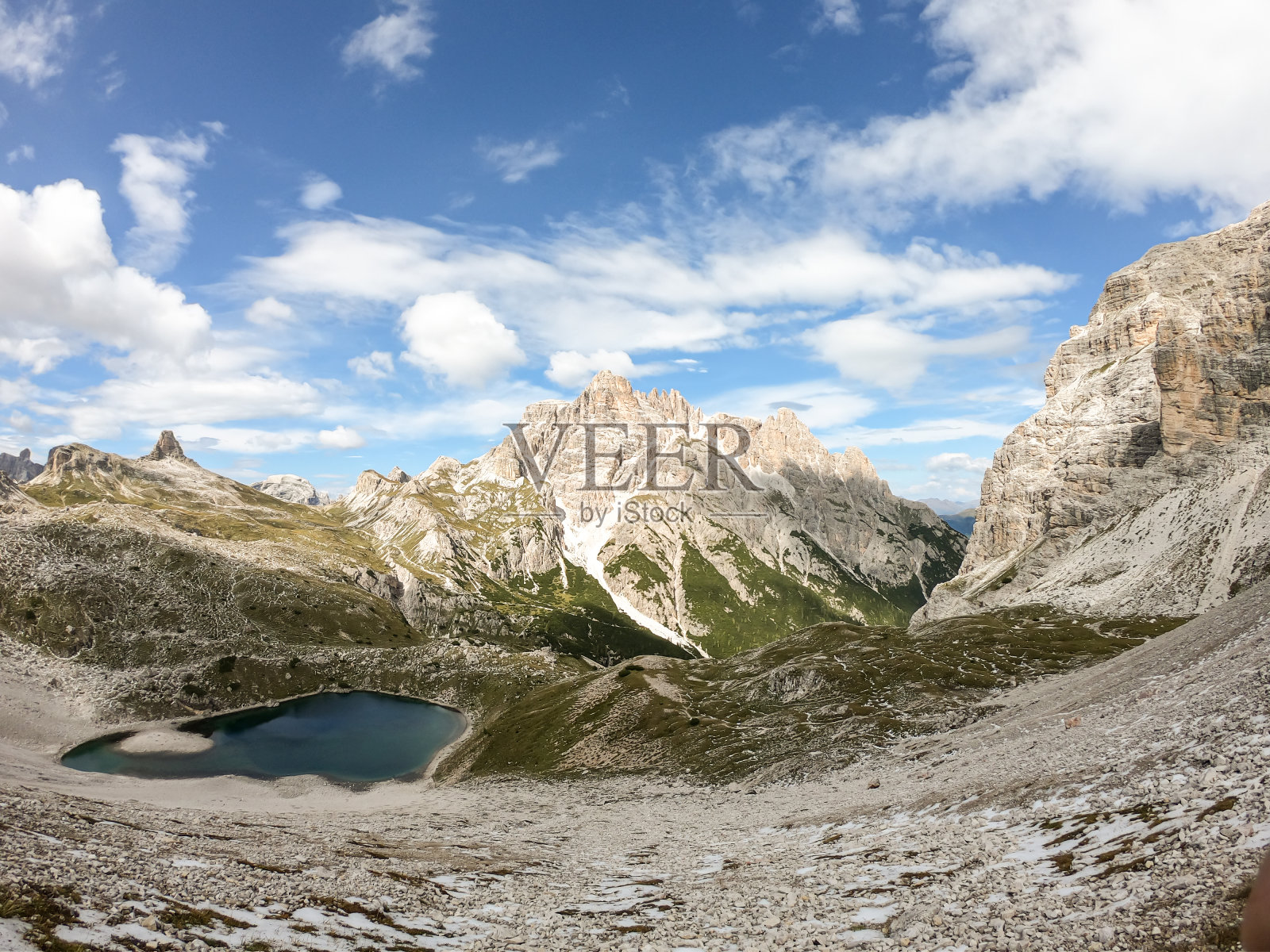 意大利白云石的全景。周围有陡峭的山坡。在一个小山谷的底部有一个深蓝色的小湖。天空中布满了柔和的云彩。原始的风景照片摄影图片