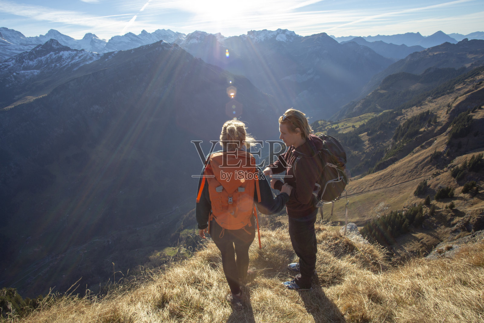 早晨，徒步旅行者在阳光明媚的山脊上休息照片摄影图片