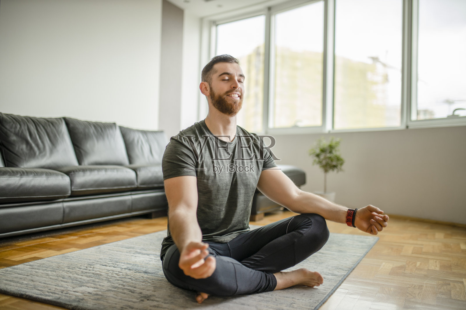 年轻人微笑着练瑜伽，莲花式，莲花式，健身，穿着运动服在家照片摄影图片