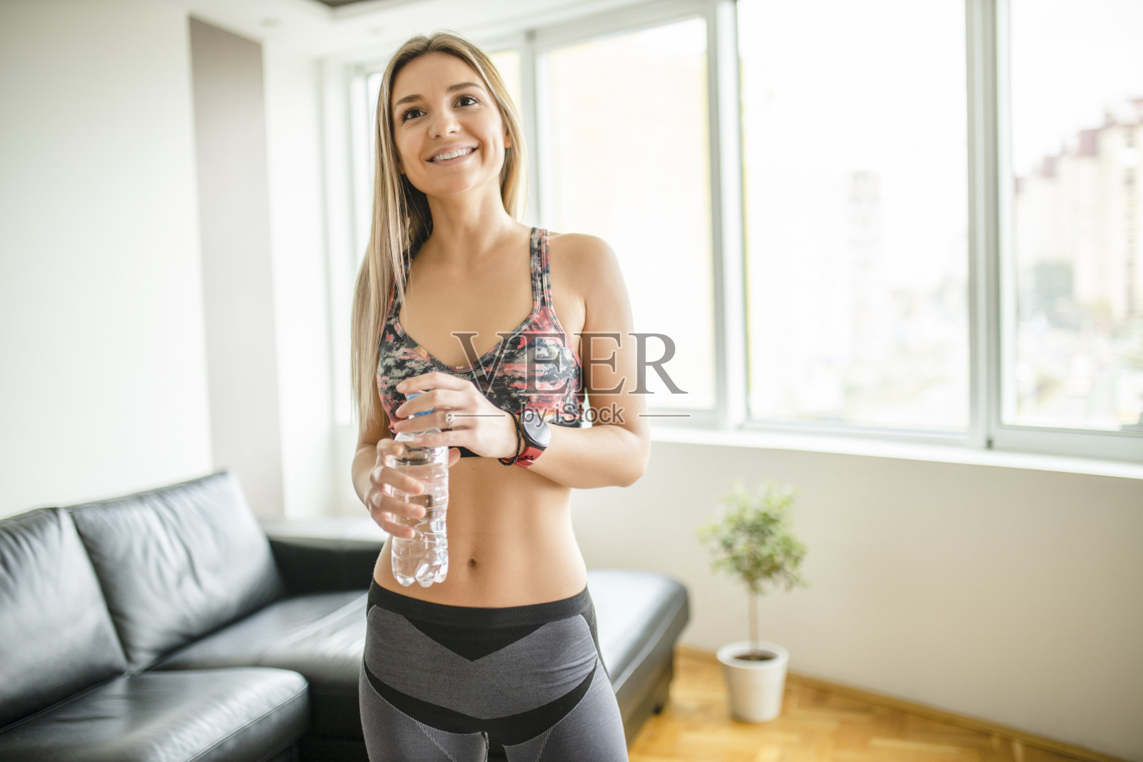 年轻的运动女性在她的公寓里锻炼和喝水照片摄影图片