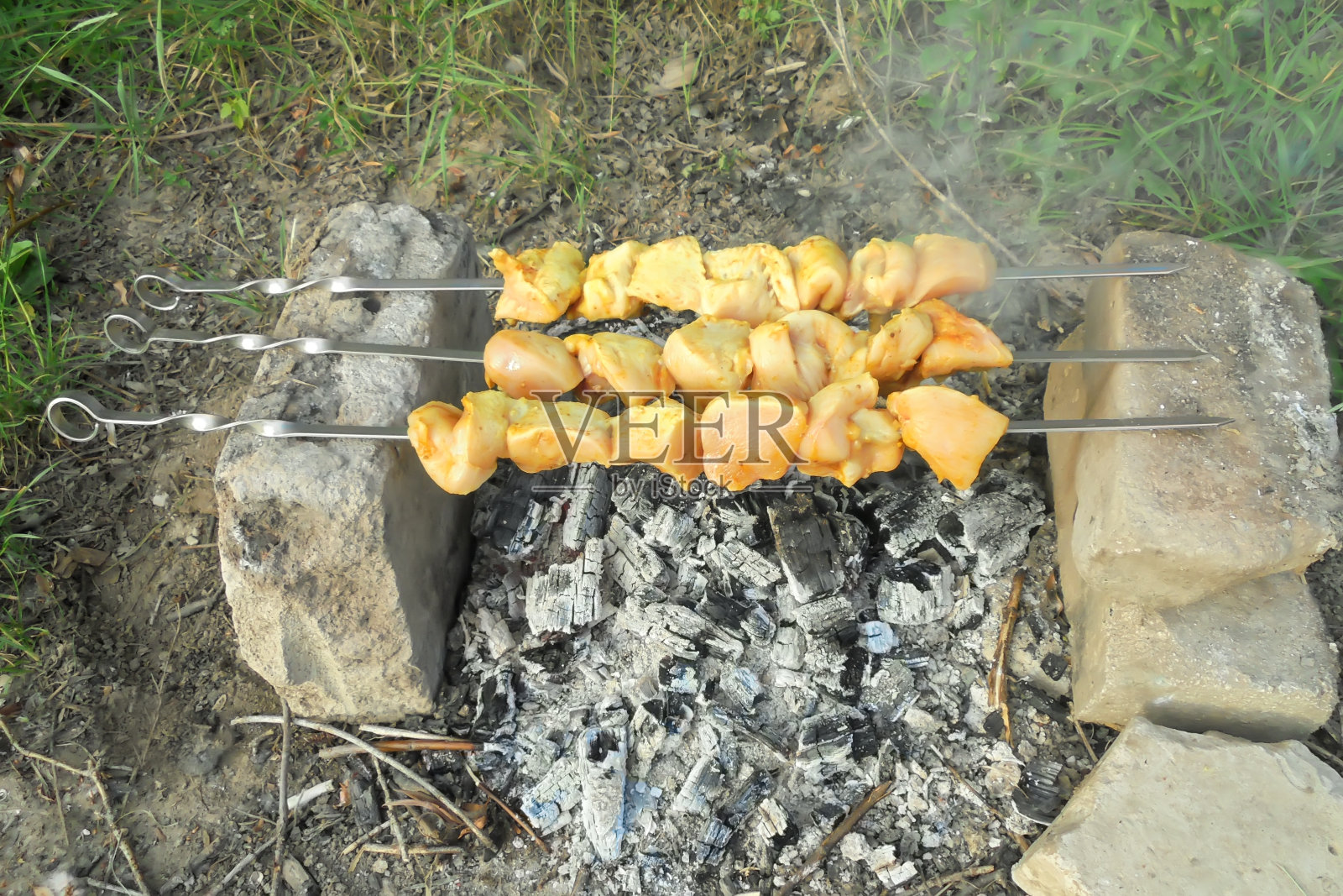 鸡肉片是用三串串成的烤肉串，在野外的火上炸照片摄影图片