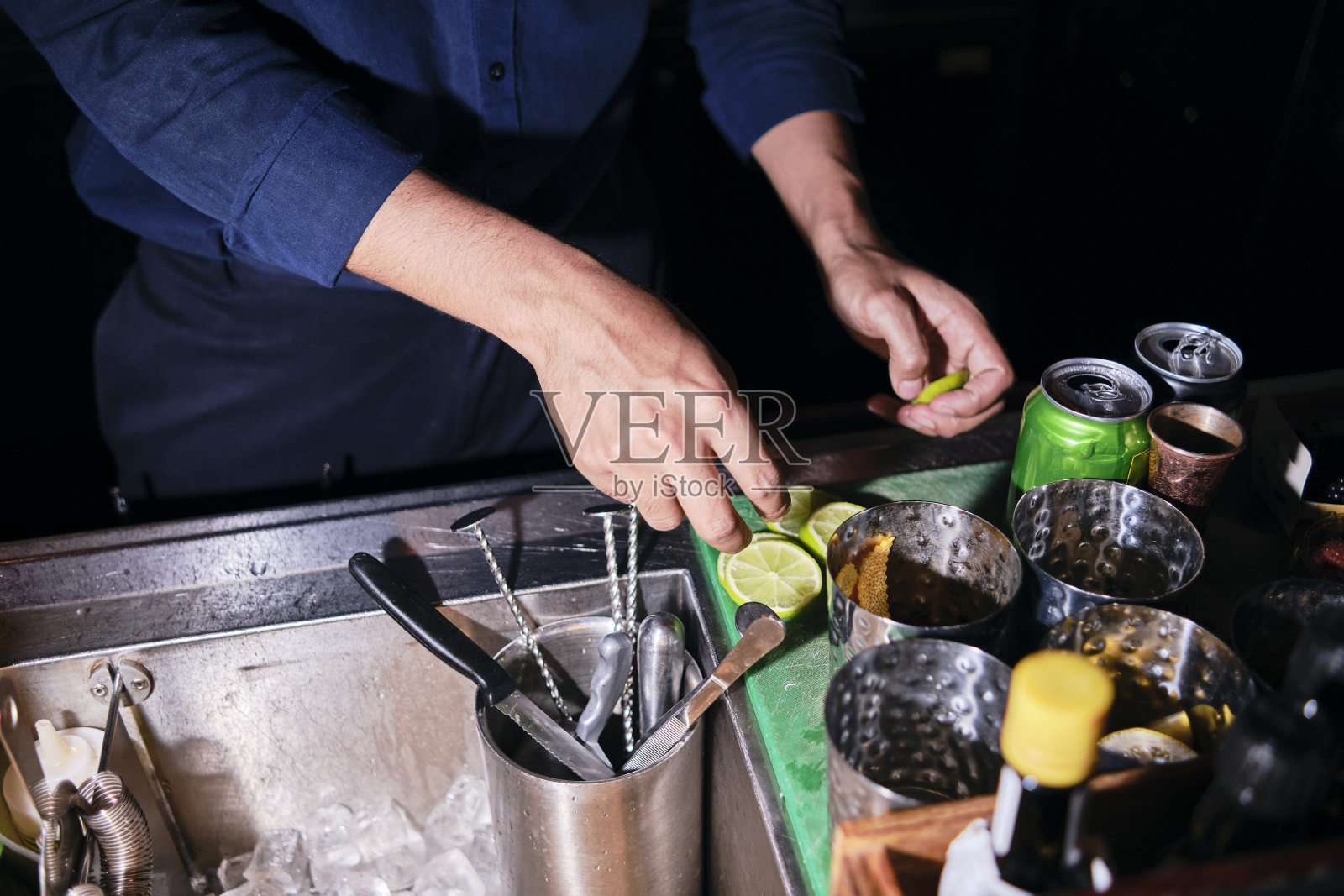男酒保在黑酒吧剥柠檬。照片摄影图片