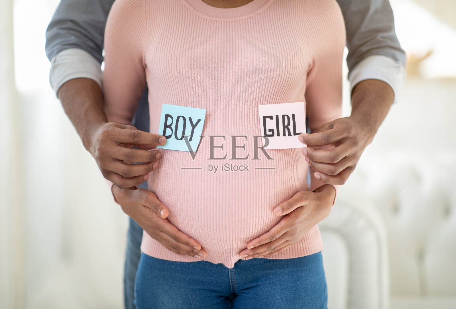 爱非裔美国夫妇抱着男孩和女孩的卡片靠近怀孕的肚子，近距离观看照片摄影图片