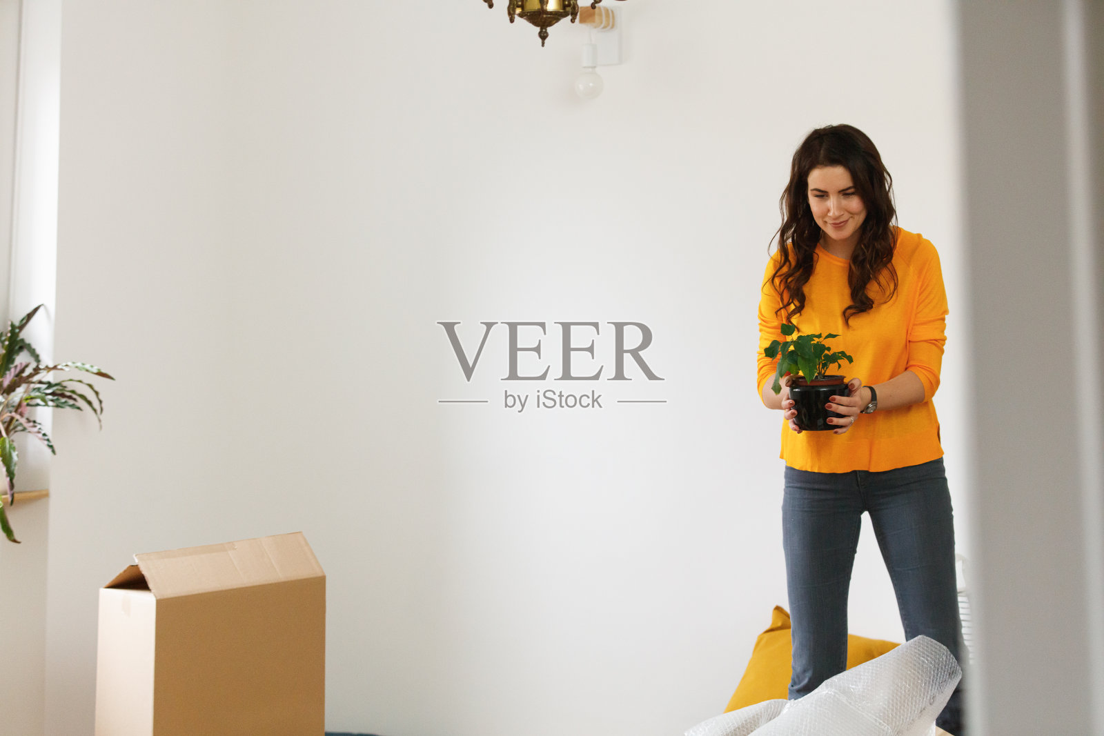 女人收拾房子搬家，手里拿着小盆栽照片摄影图片