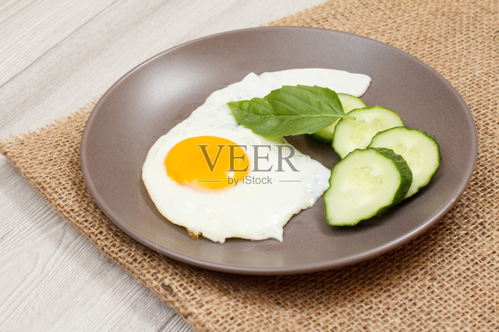 盛上煎蛋、鲜切黄瓜及罗勒叶。照片摄影图片