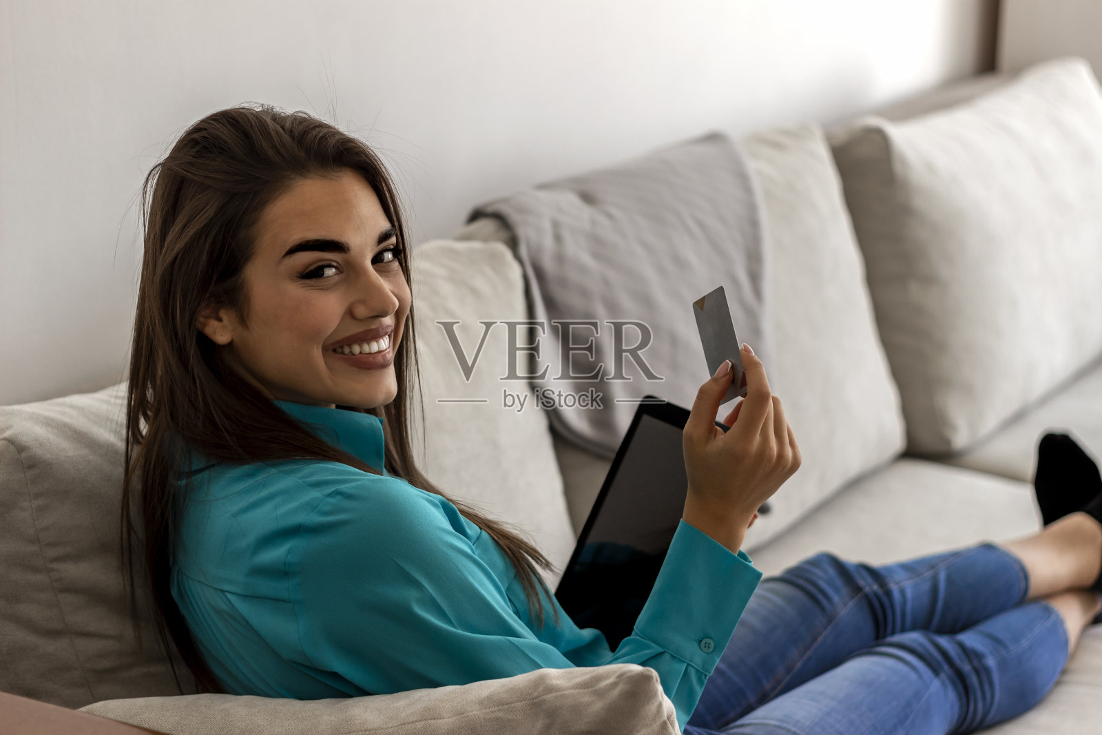 女孩持有信用卡和数字平板电脑的后视图，而她正在网上购物照片摄影图片