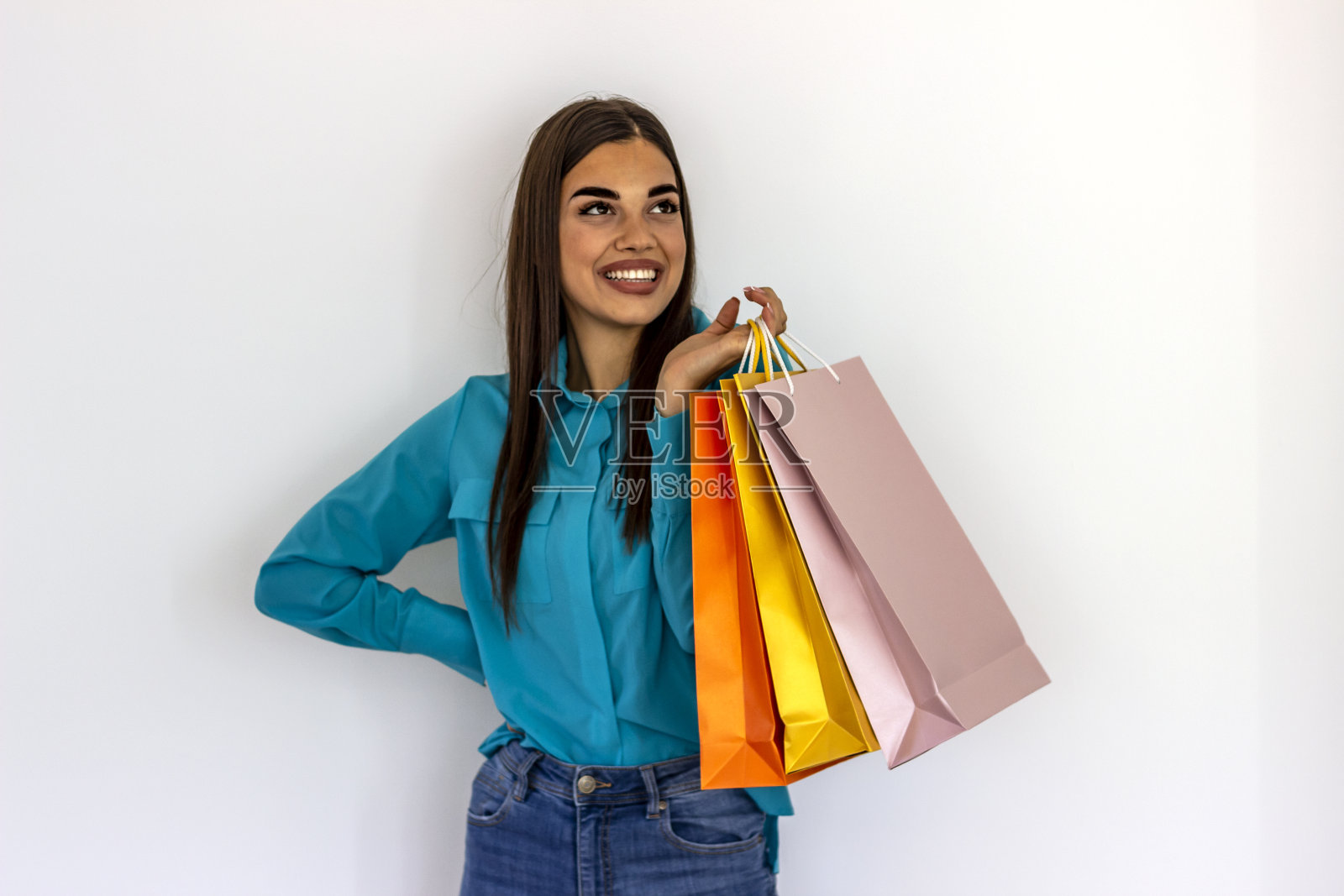 一个兴奋的年轻女子举着她五颜六色的购物袋。照片摄影图片