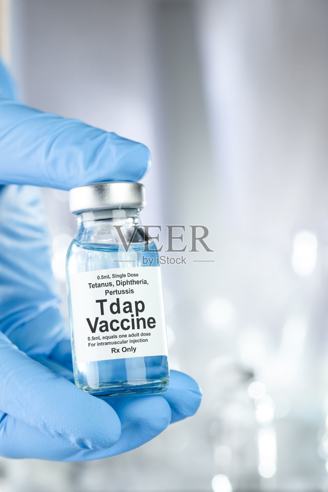 保健理念:一只手拿着蓝色医用手套，手里拿着百日咳、破伤风、白喉、百日咳或百日咳疫苗瓶照片摄影图片