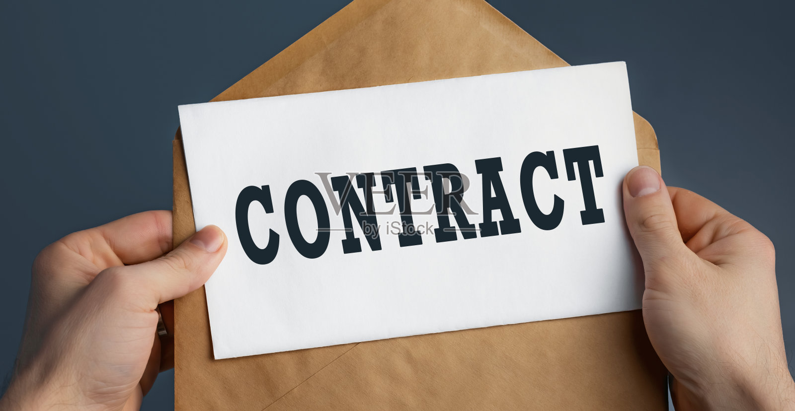 男人的手拿着工艺信封与字合同在蓝色的背景照片摄影图片