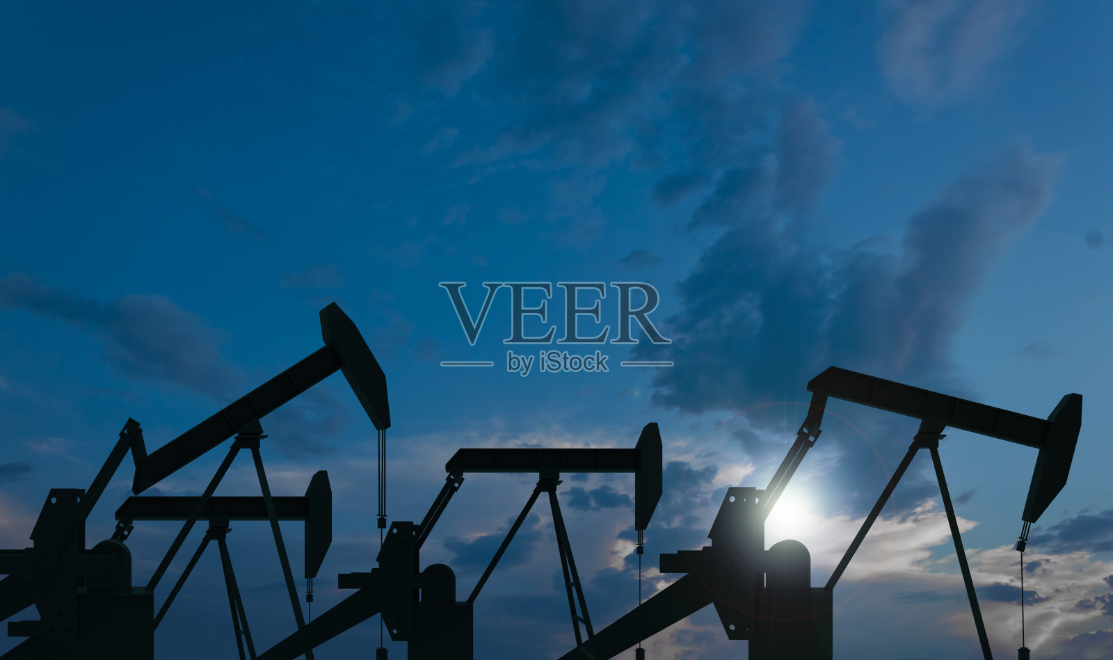 在晚油田中，泵是运行的。照片摄影图片