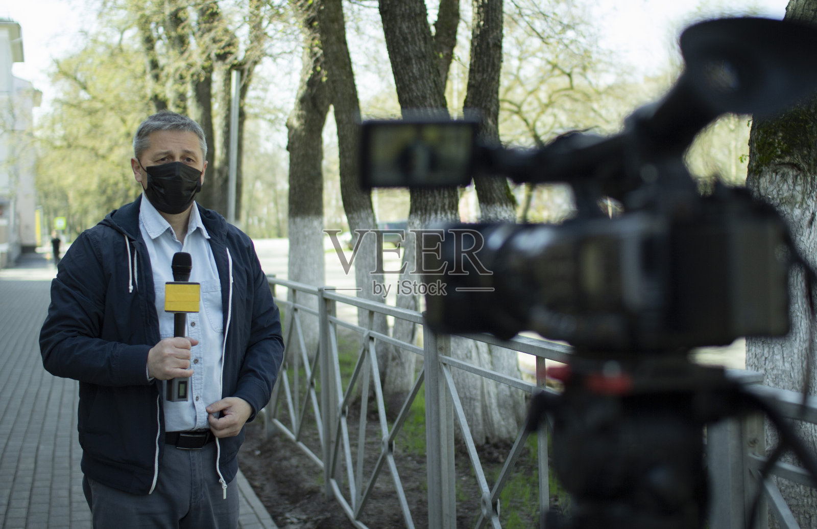 一位中年的欧洲记者戴着医用防护面具在一个荒芜的城市里进行报道。照片摄影图片