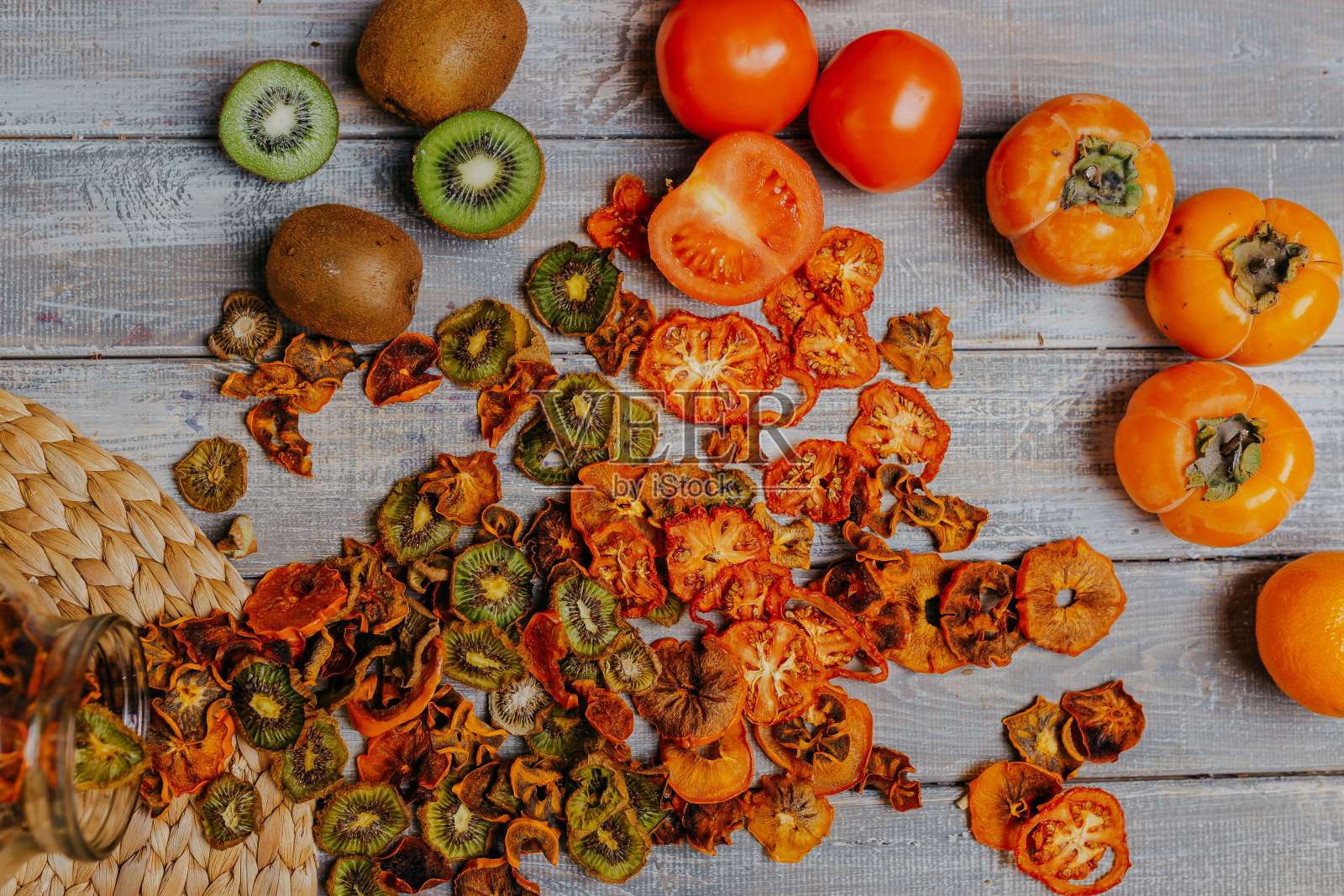 果片装在罐子里，木桌上放着新鲜的水果。水果皮用的薯片。健康食品。猕猴桃和番茄片。照片摄影图片