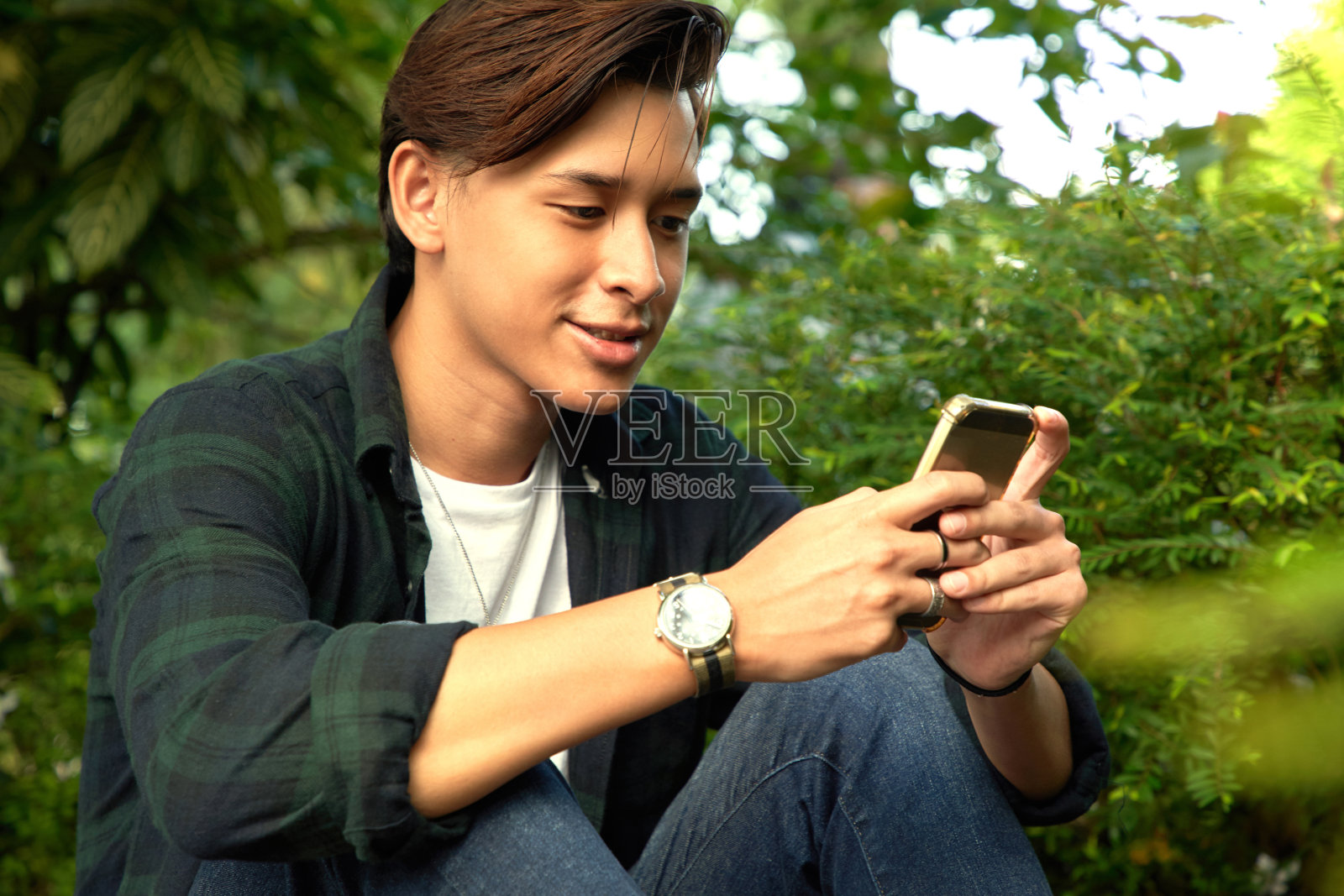 帅哥坐在长凳上享受他的智能手机照片摄影图片