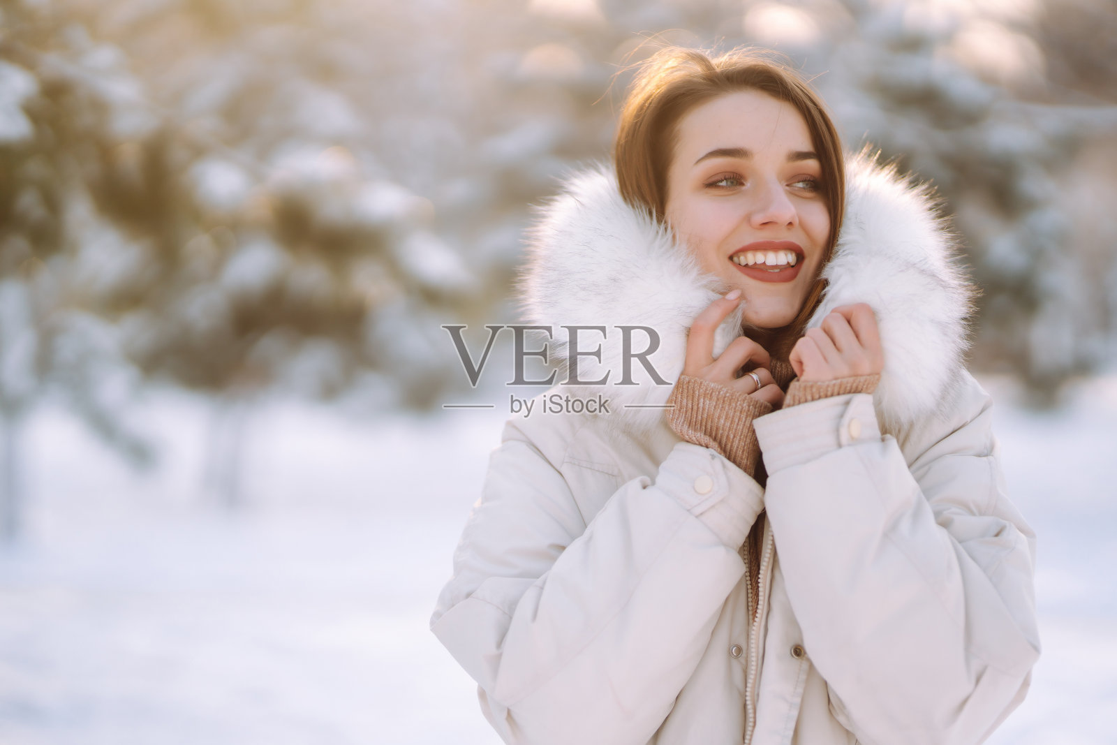 一个穿着冬装的漂亮女人在白雪覆盖的公园里摆姿势照片摄影图片