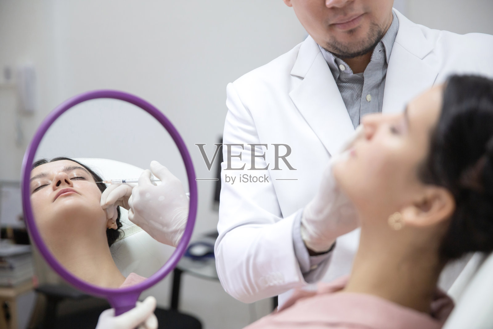 年轻女子在美容院接受美容注射。美容师在女性病人脸上进行整容注射。美容注射、光疗、振兴、返老还童照片摄影图片