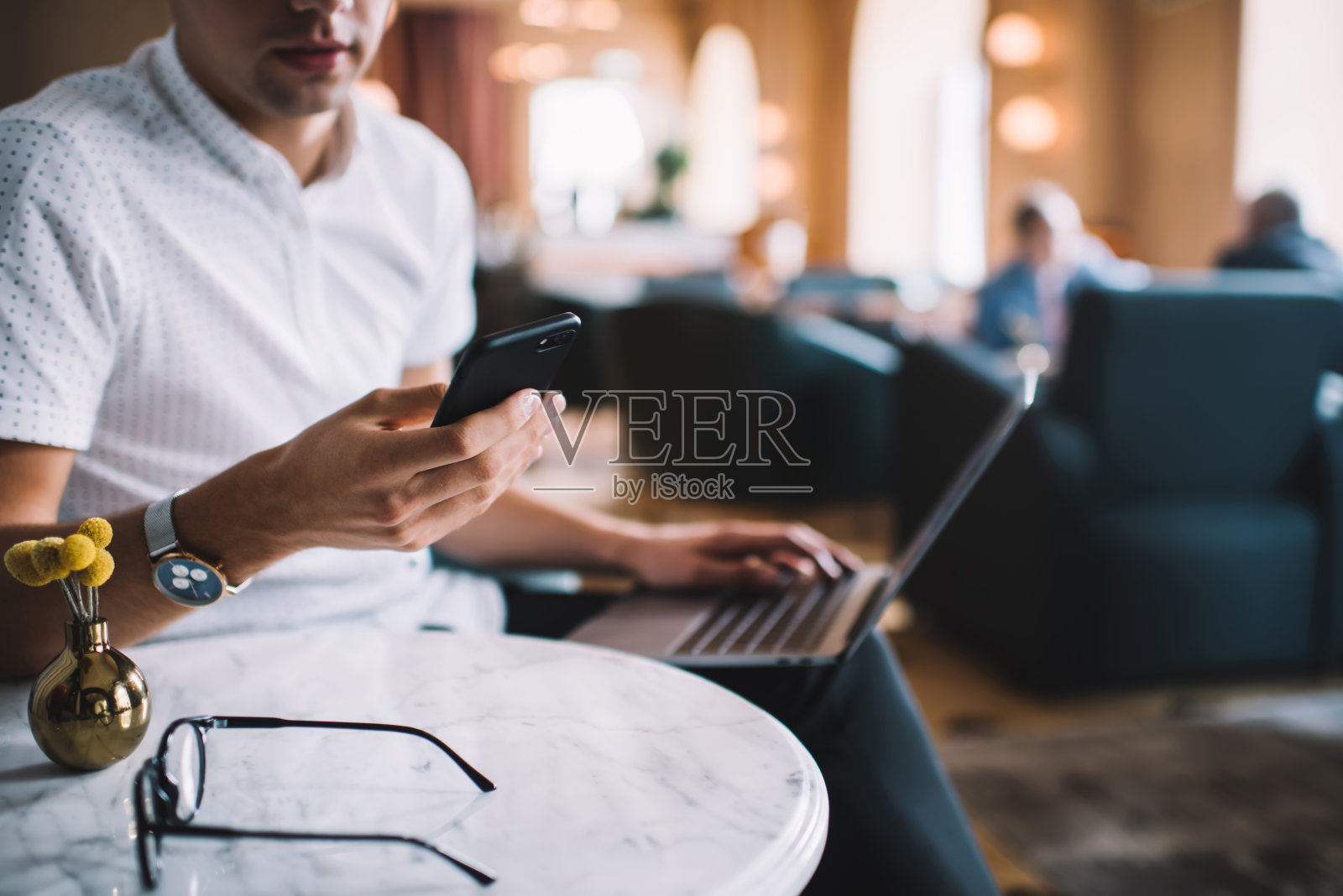 在咖啡馆里浏览智能手机和用笔记本打字的作物男照片摄影图片