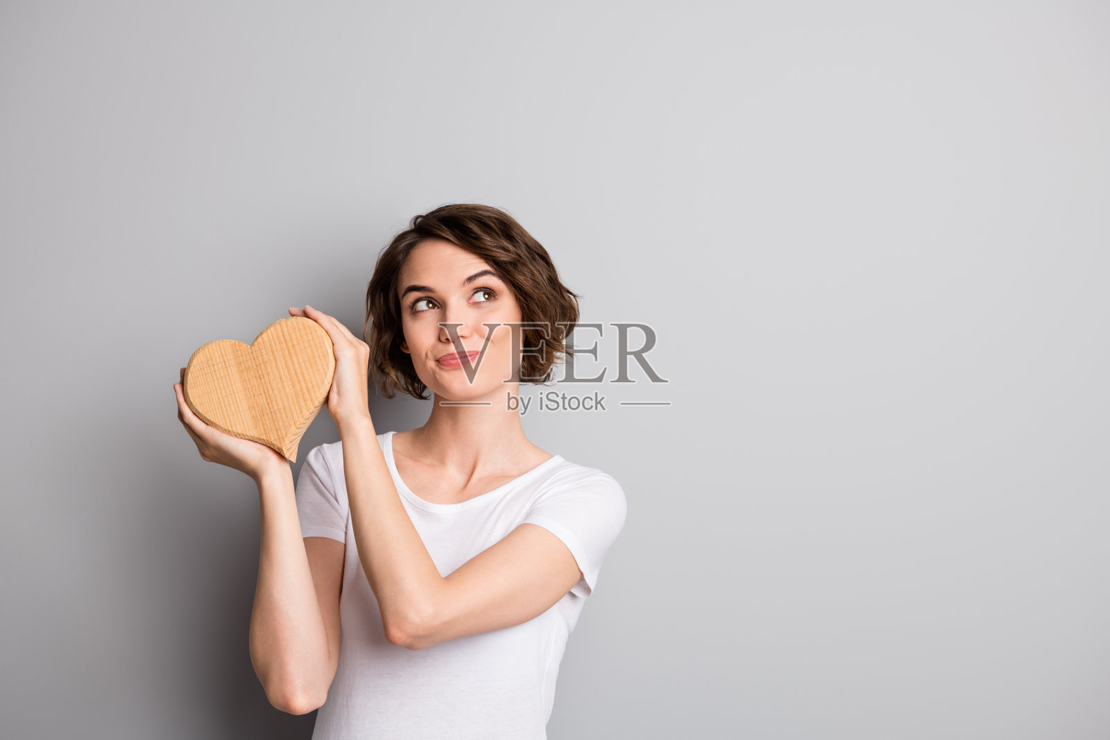 年轻美丽的照片，梦幻浪漫的女孩抱着心爱像看空的空间孤立的灰色背景照片摄影图片