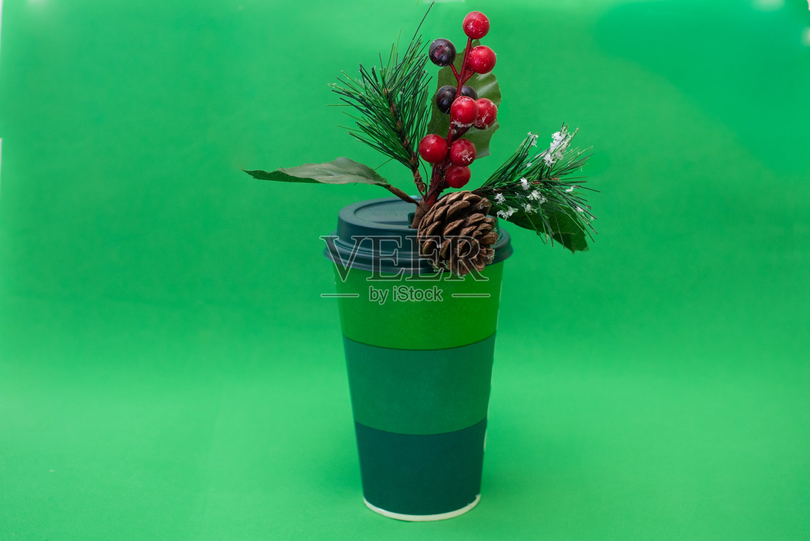 绿色一次性纸杯和松树枝红色浆果和松果在绿色背景照片摄影图片