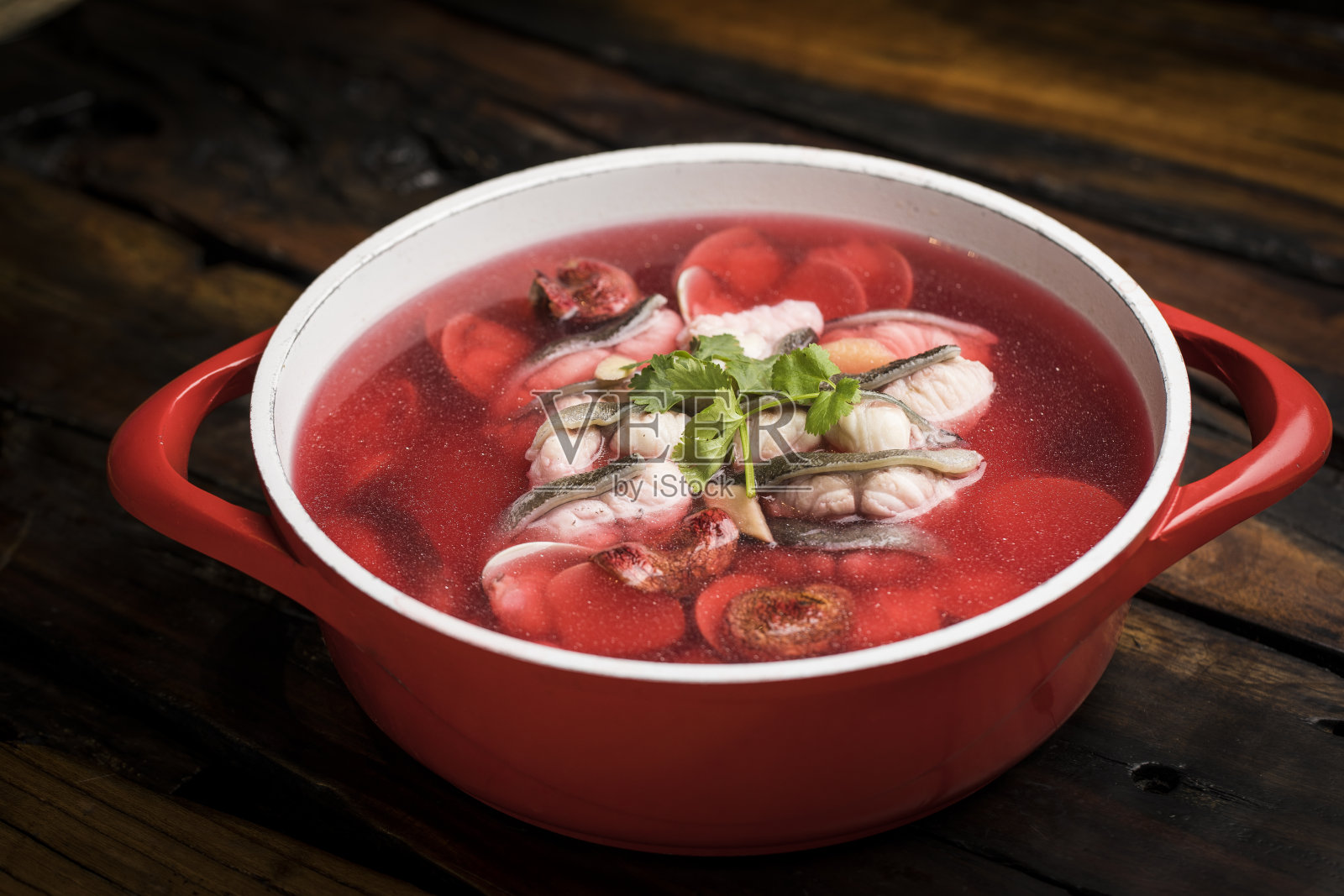 鲜红蘑菇鱼汤，用红锅煮。照片摄影图片