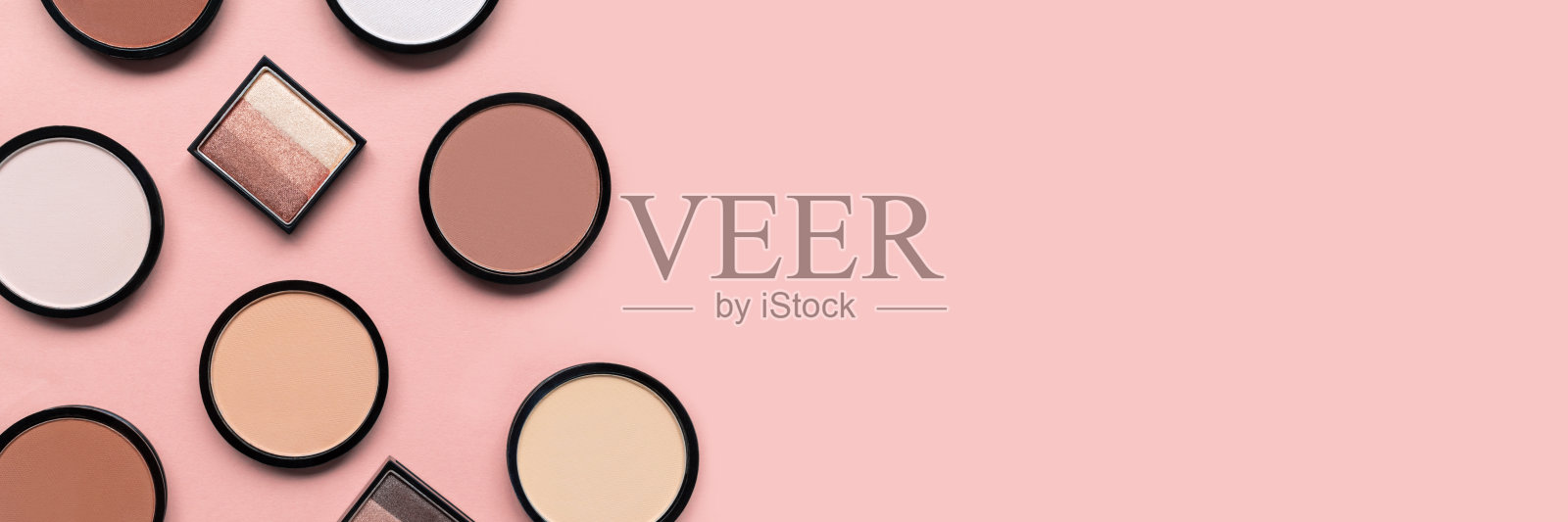 米色腮红，眼影和矿物粉饼粉在柔和的粉红色背景。横幅。文本。副本的空间。前视图。时尚的颜色。化妆。美容产品。色调的基础。平的。照片摄影图片