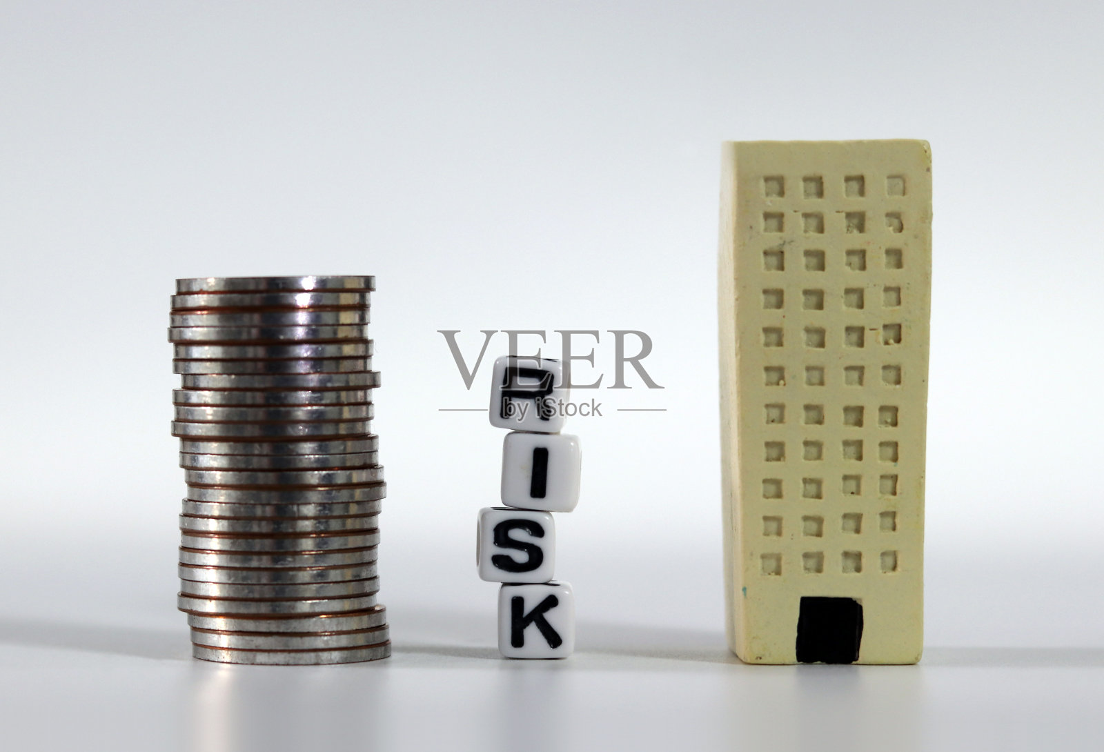 风险管理的概念。白色方块与风险字和微型建筑和一堆硬币。照片摄影图片