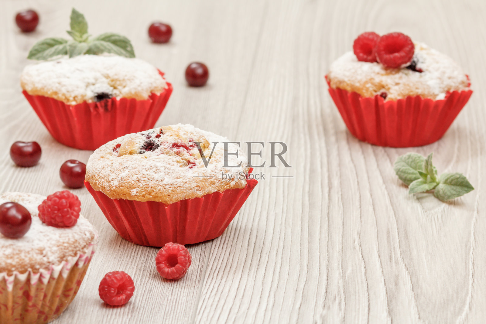 撒上糖粉、新鲜覆盆子和薄荷的自制小蛋糕。照片摄影图片