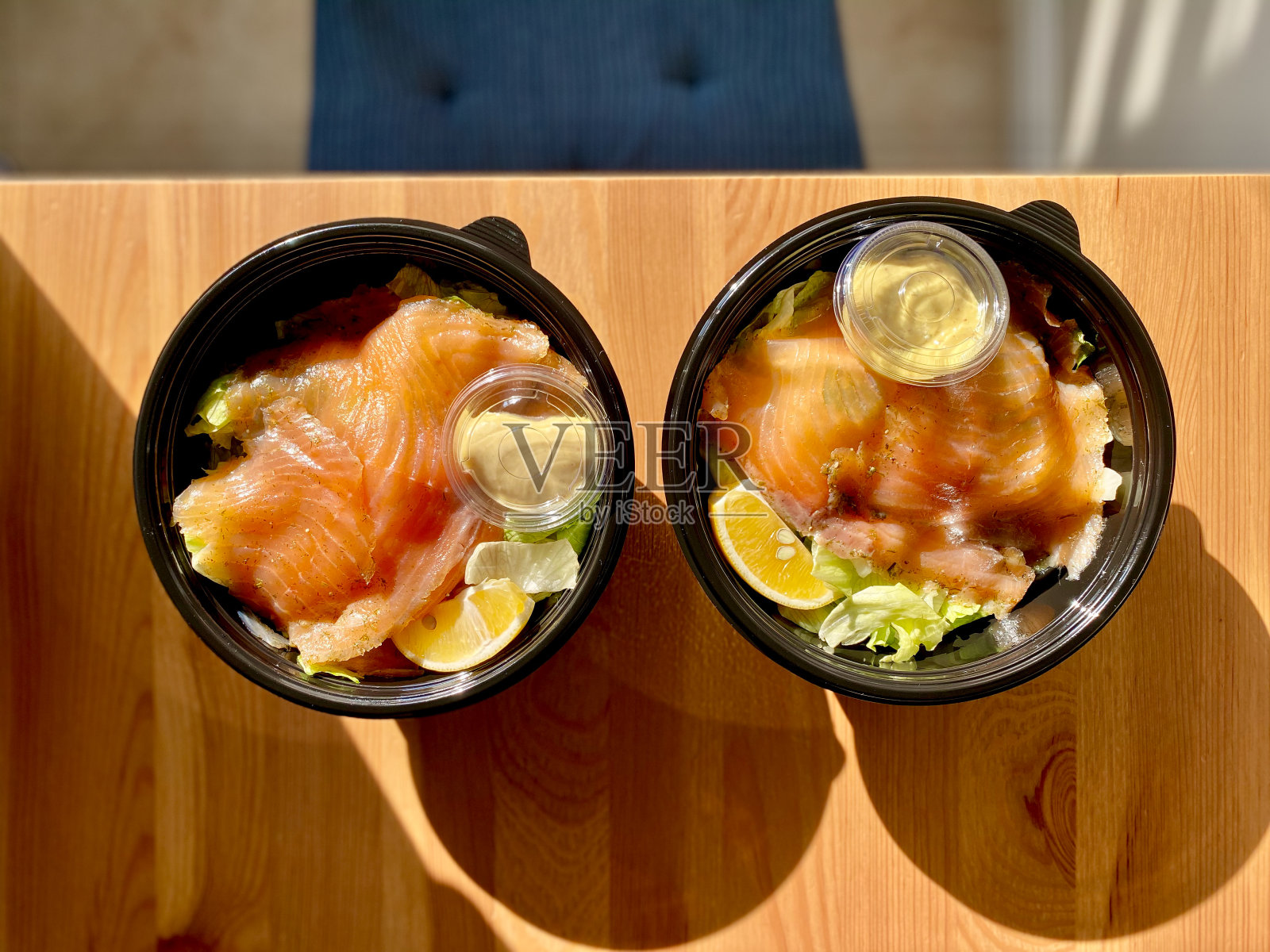 带走黑色塑料碗装的三文鱼沙拉和芥末酱包。照片摄影图片