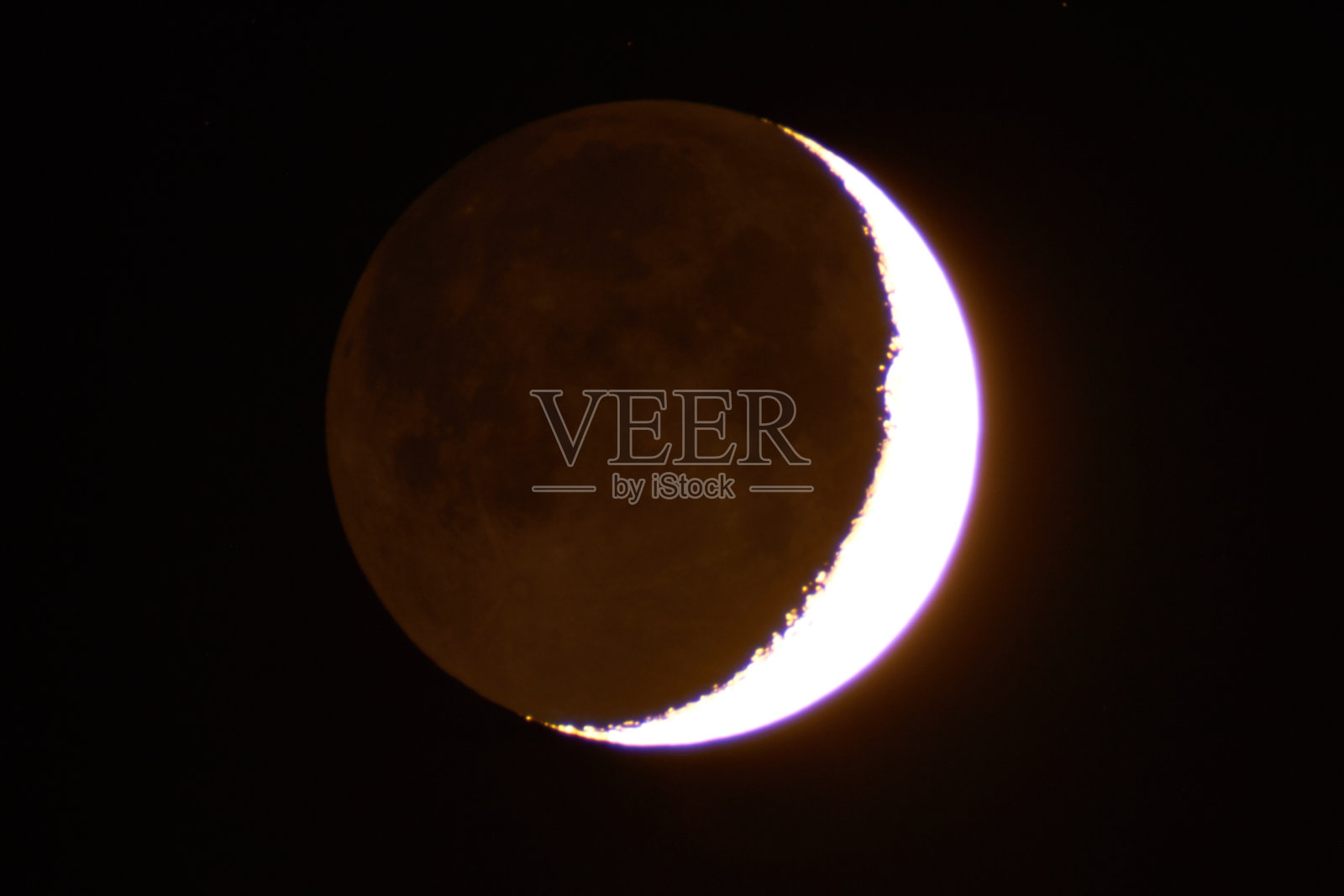 年轻的月亮通过长焦望远镜拍摄。照片摄影图片