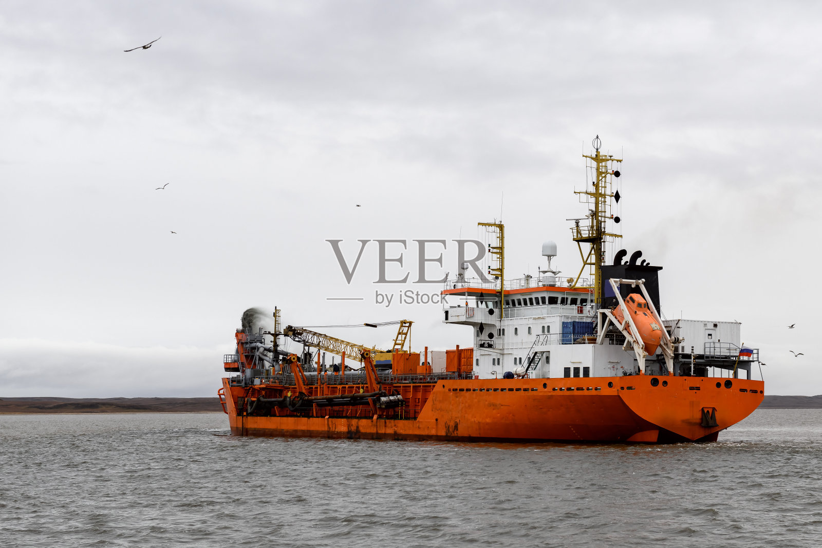 从事挖泥工作的船只。在海上工作的挖泥船。从水环境中挖掘材料的船舶。照片摄影图片