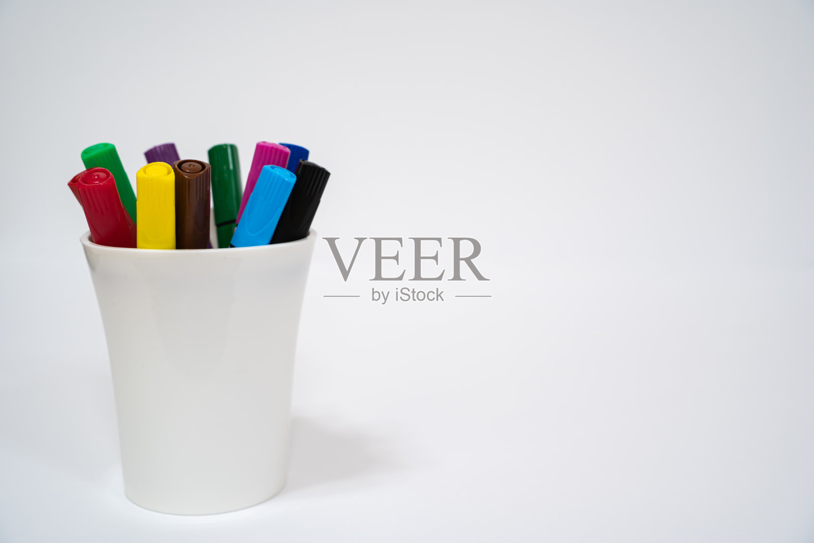 白底白杯上的一组彩色记号笔。特写镜头。副本的空间。照片摄影图片