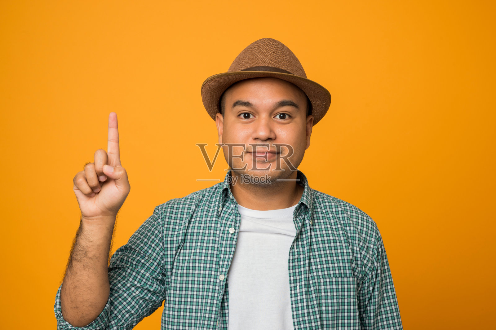 度假的游客用手指向外指了指第一个，同时自信而快乐地独自站在黄色的背景上。照片摄影图片