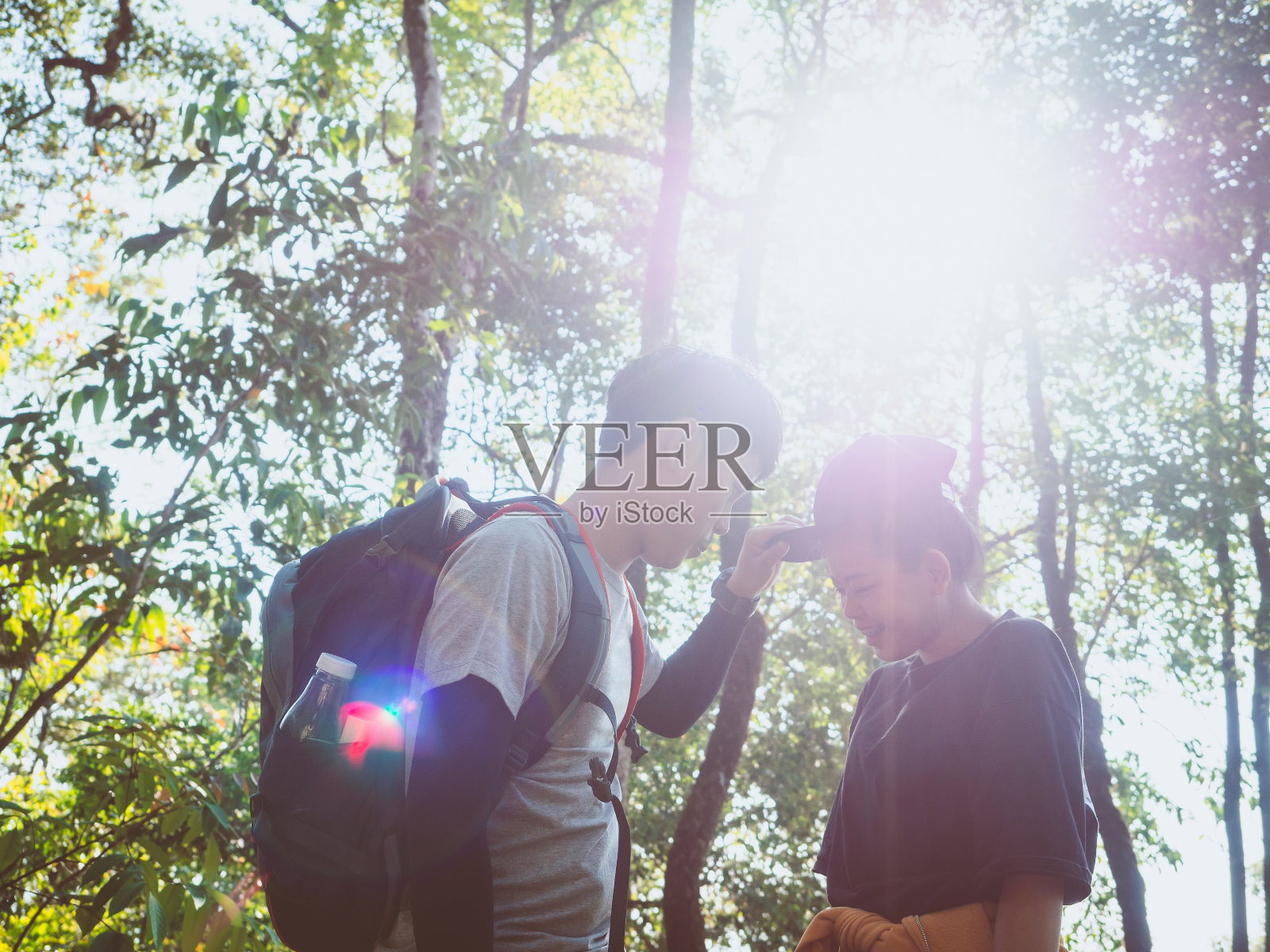 从快乐的年轻夫妇的冒险旅行概念享受徒步旅行在夏天的阳光透过树木。照片摄影图片