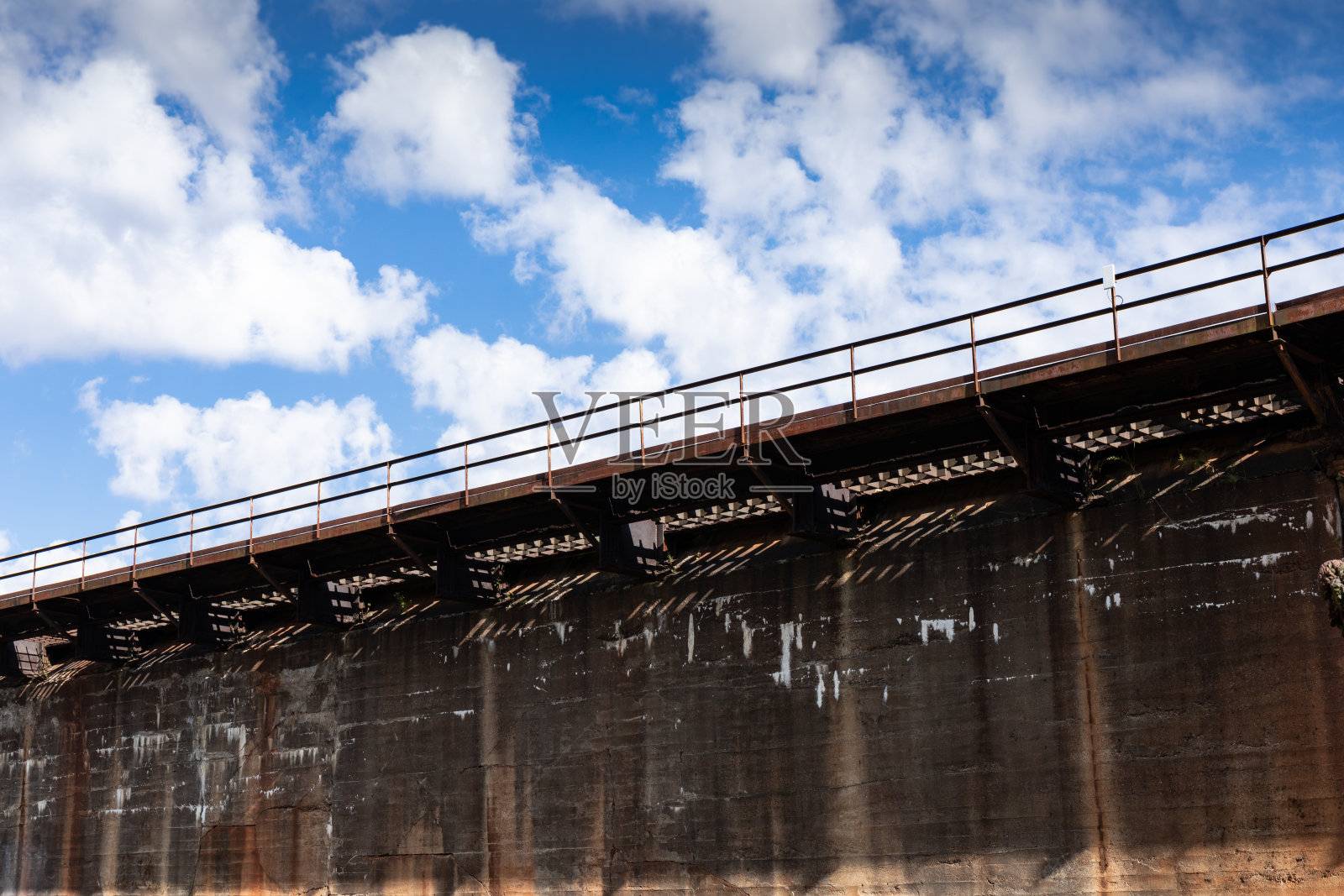 长而高的工业混凝土墙和生锈的金属猫步前蓝天和云彩照片摄影图片