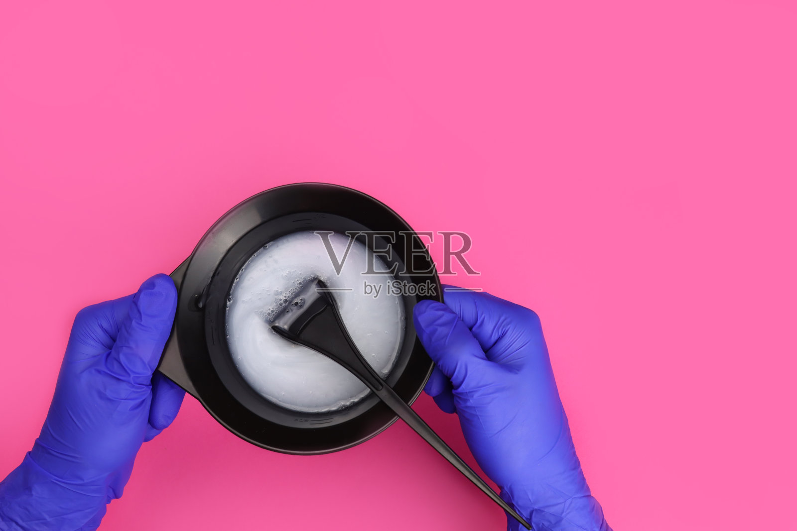 发型师手持染发剂，用刷子将染发剂放入混色碗中照片摄影图片