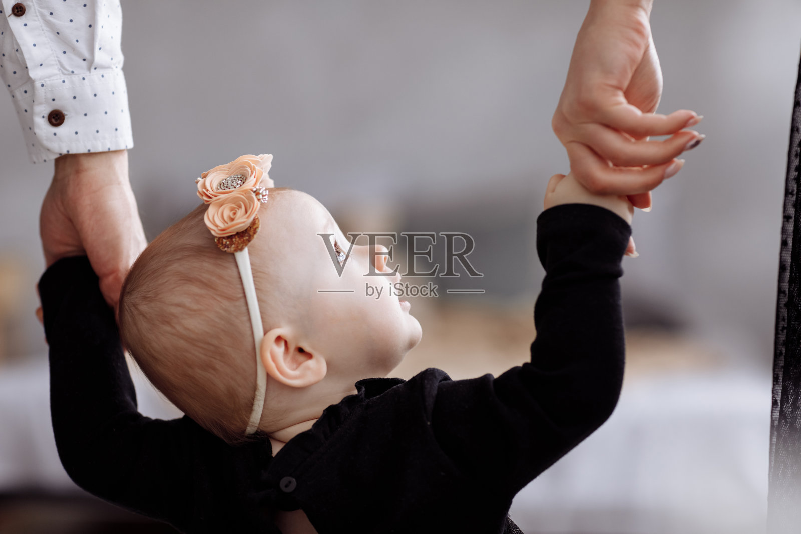 妈妈，爸爸牵着女儿一起在家享受时光。往下看腿。母亲节，父亲节，宝宝节。年轻的家庭度假理念，关爱和支持下一代。照片摄影图片