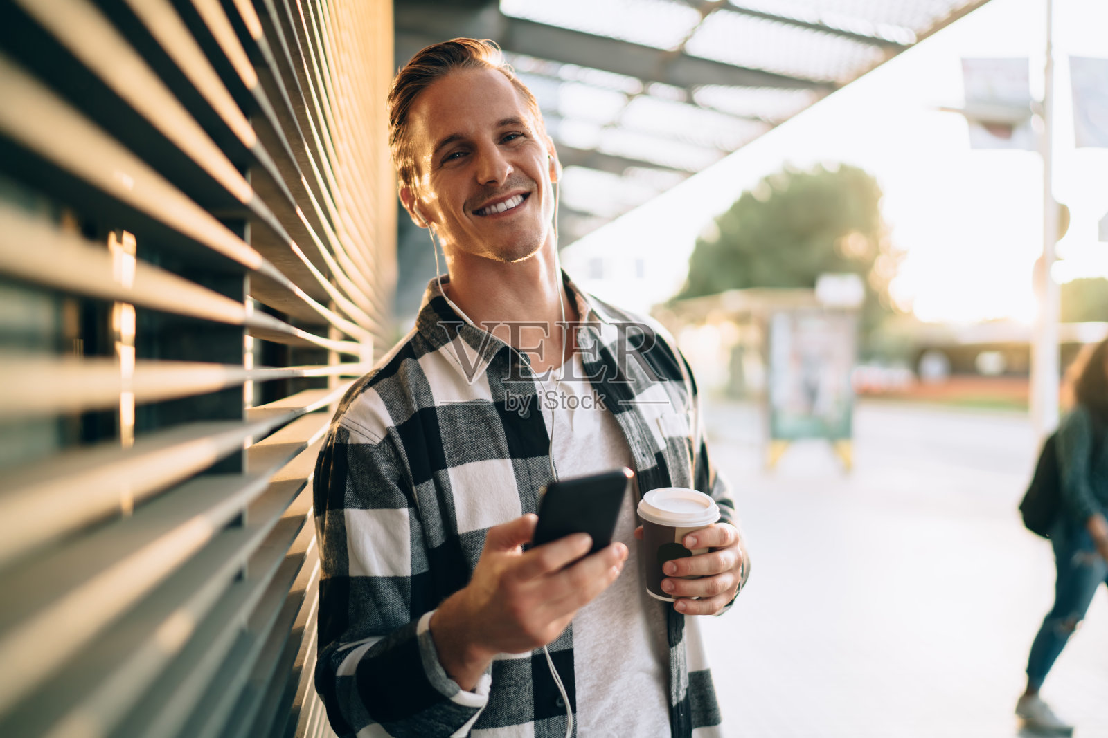 一个快乐的白人嬉皮士在街上享受智能手机上的播放器和带有完美声音的连接配件，一个20多岁的千禧一代男性在街上通过智能手机听音乐照片摄影图片