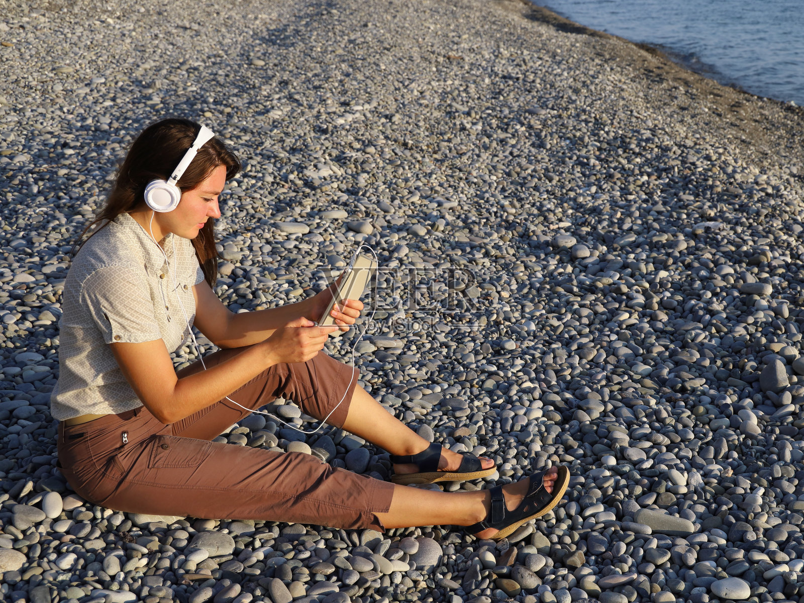 年轻女子戴着白色耳机，手里拿着平板电脑照片摄影图片
