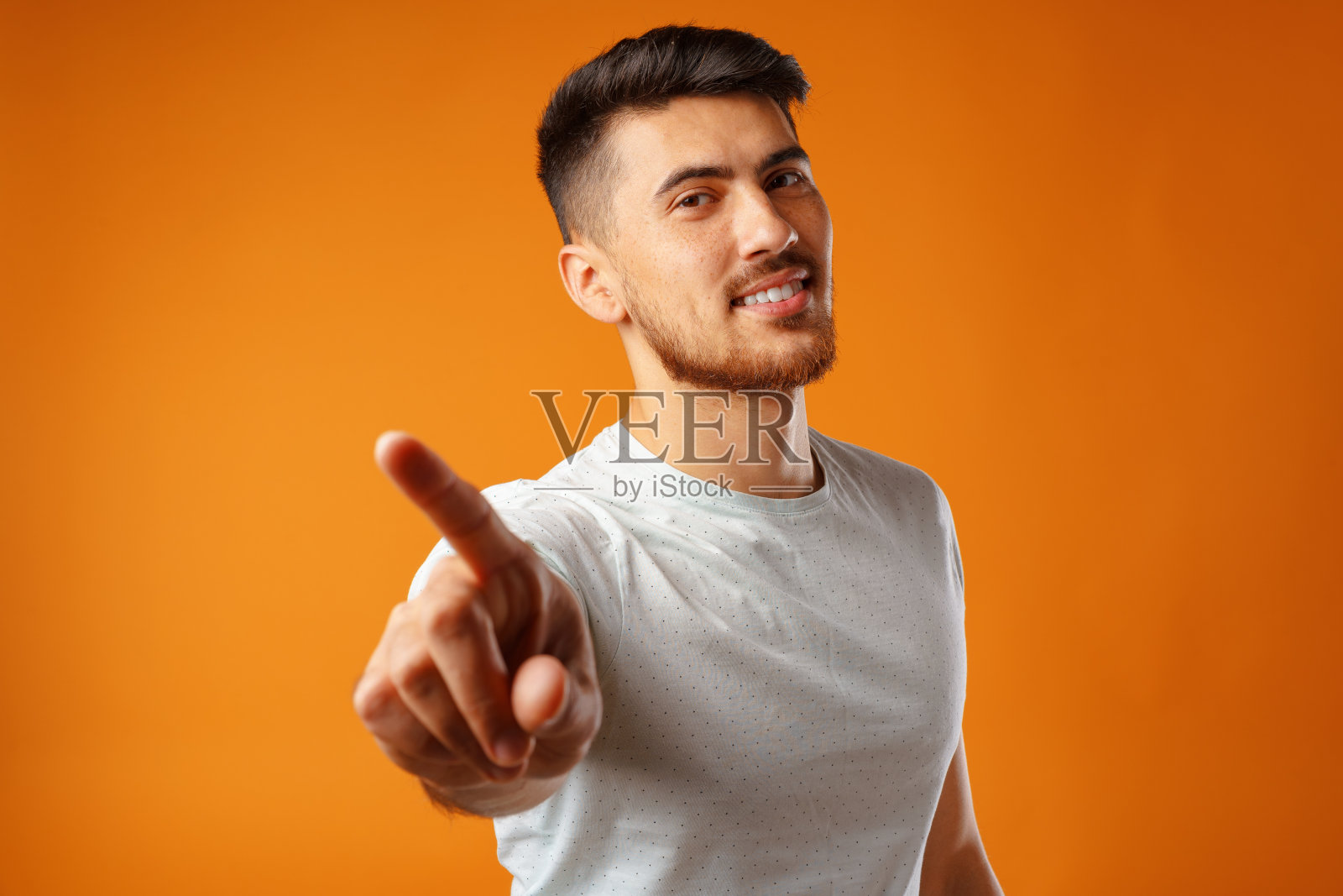 穿着白色t恤的酷小伙微笑着指着你照片摄影图片